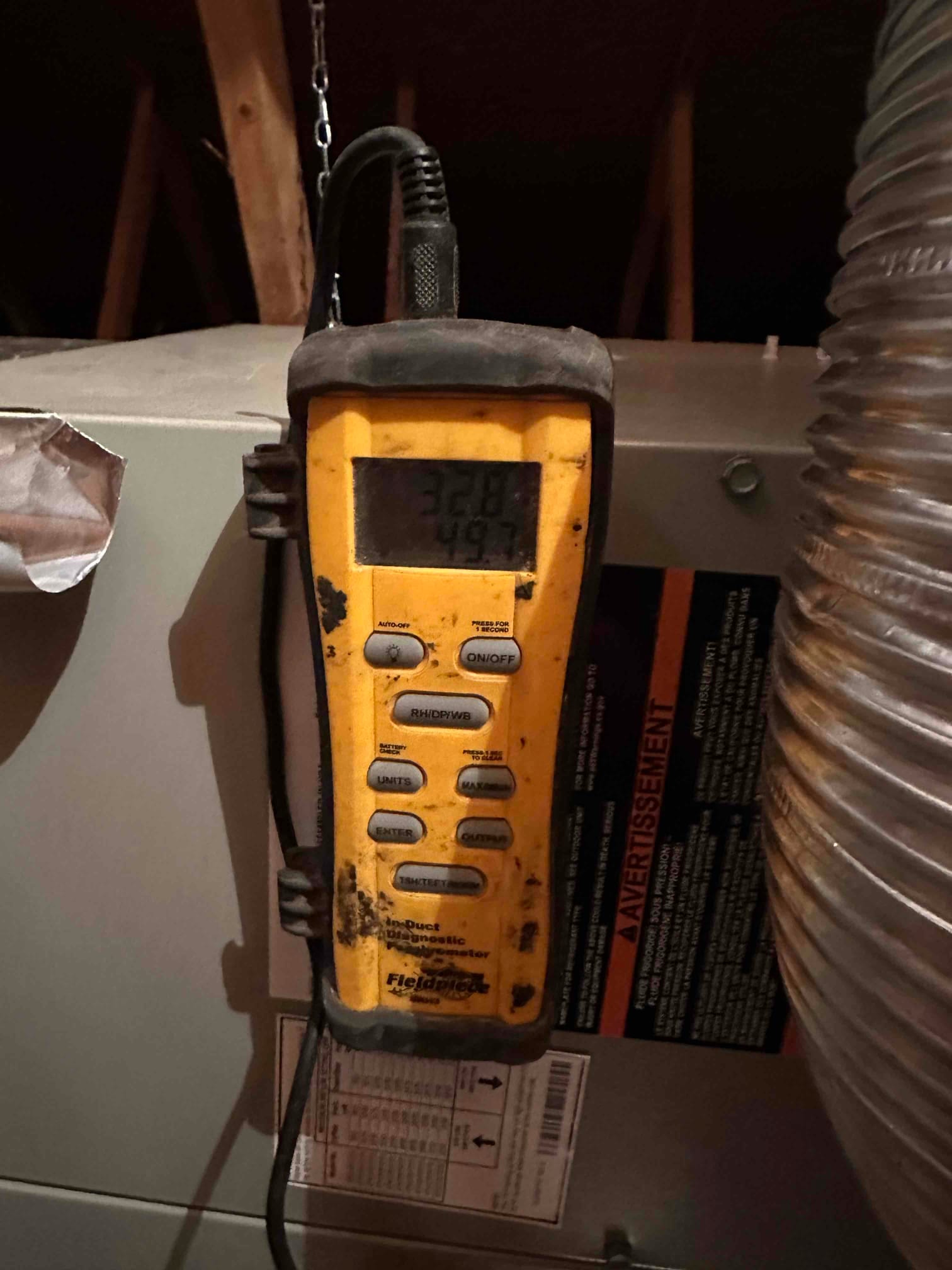 Digital thermometer mounted near the air handler shows supply temperature of 49.7 degrees during cooling operation.