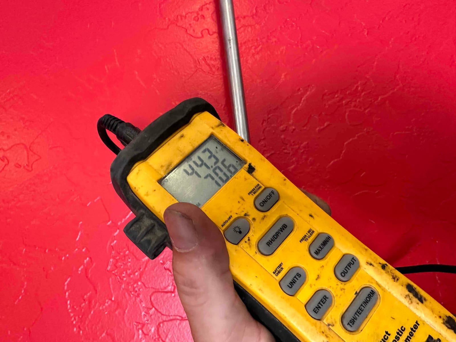 Digital thermometer probe used for air temperature measurement, display showing 44.3 and 70.6 degrees during system checkout.