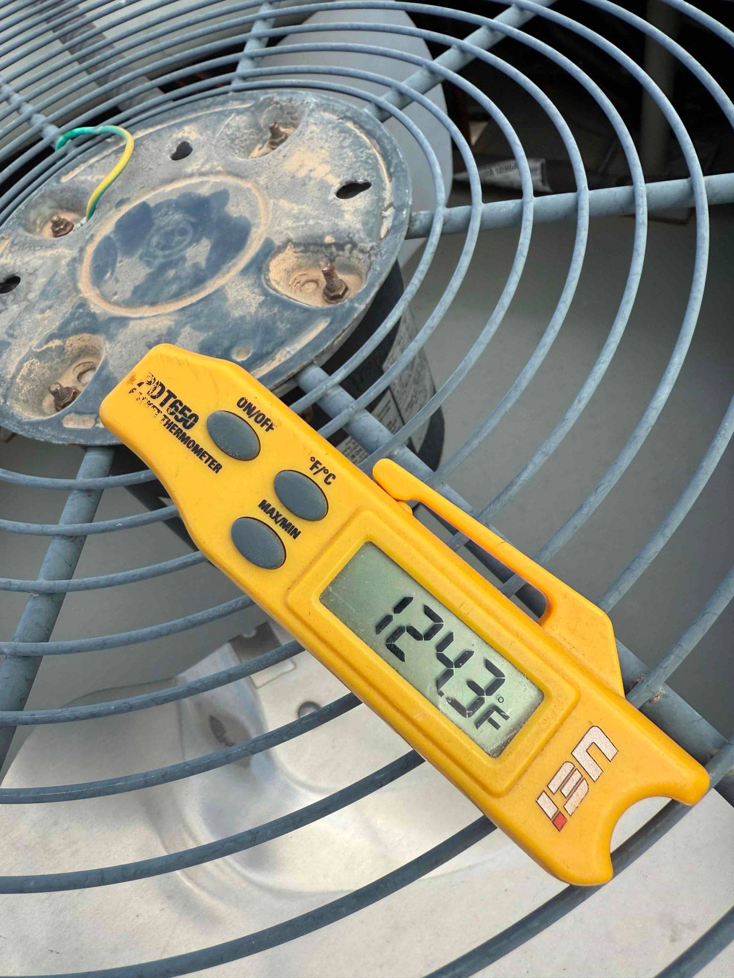 Digital thermometer shows 124.7 °F on the condenser fan area beside the motor mount plate.