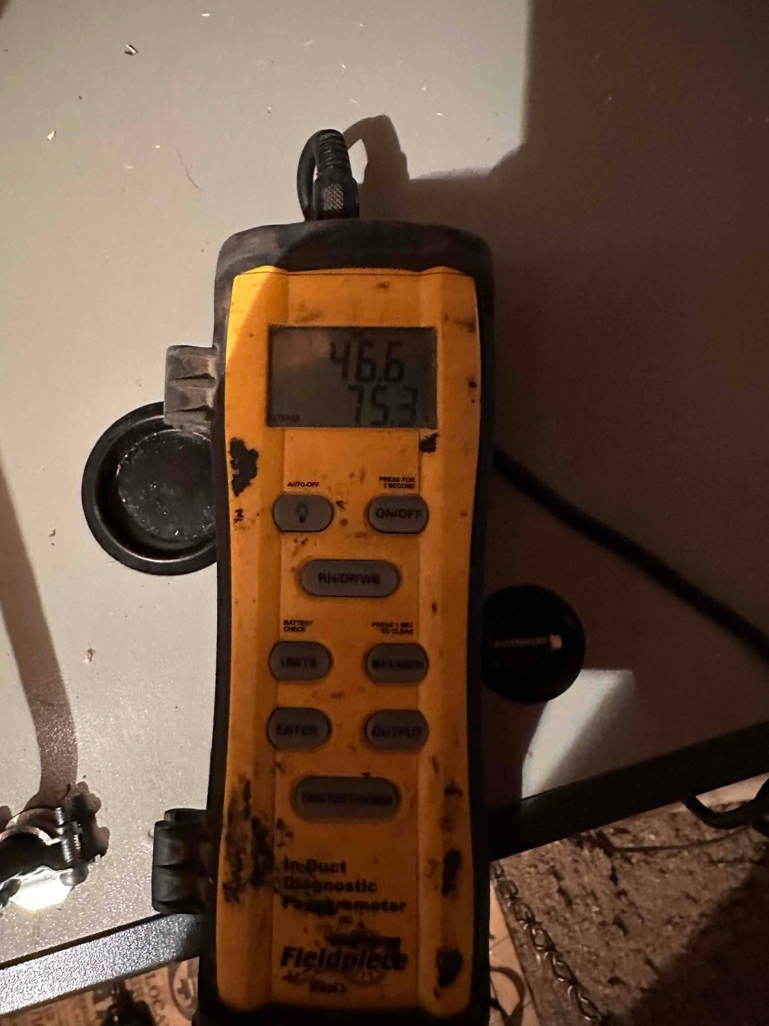Digital thermometer shows 46.6 degrees on the primary display and 75.3 degrees on the secondary display during airflow temperature checks.
