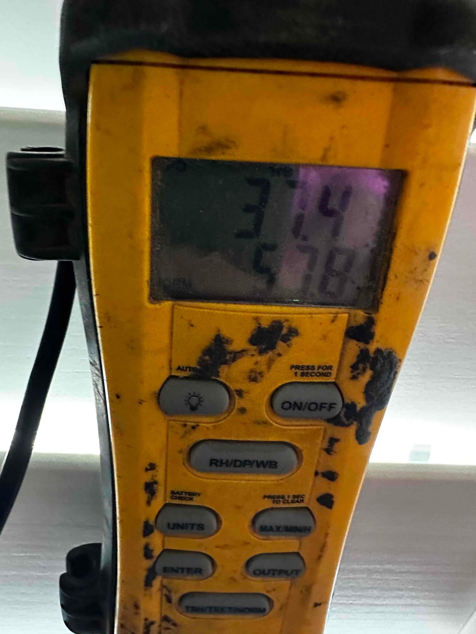 Handheld HVAC thermometer displays a temperature reading on screen during air-side checks of the new system.