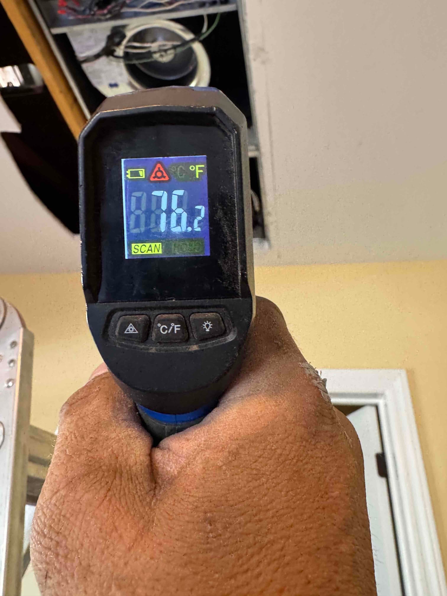 Infrared thermometer aimed at the ceiling return shows 86.2 degrees Fahrenheit during air-side temperature check.