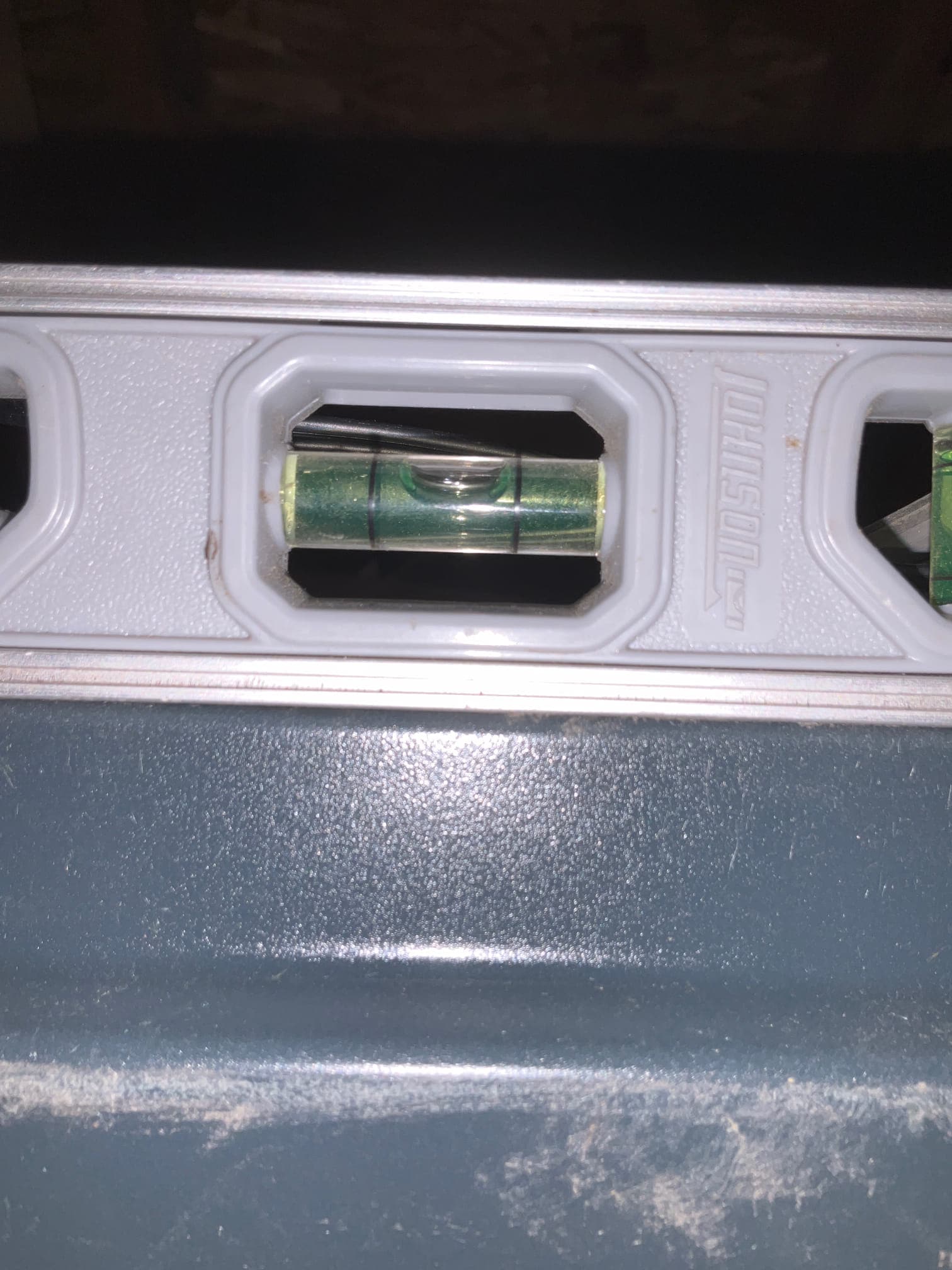 Level placed on top of installed HVAC equipment shows the bubble centered, confirming the unit is set level on its surface.