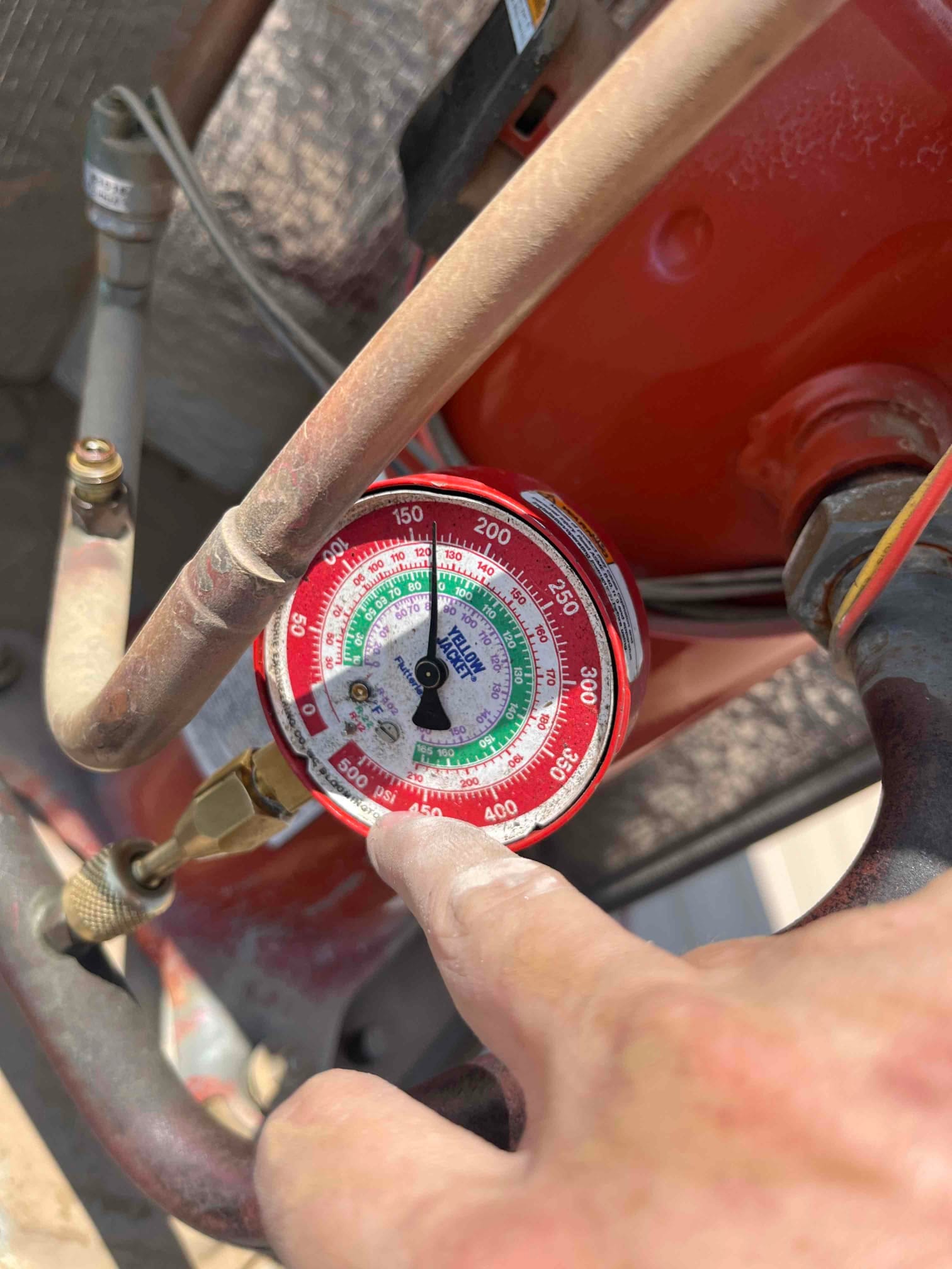 Manifold gauge on the suction side shows 110 psi low-side pressure during air conditioning system operation.