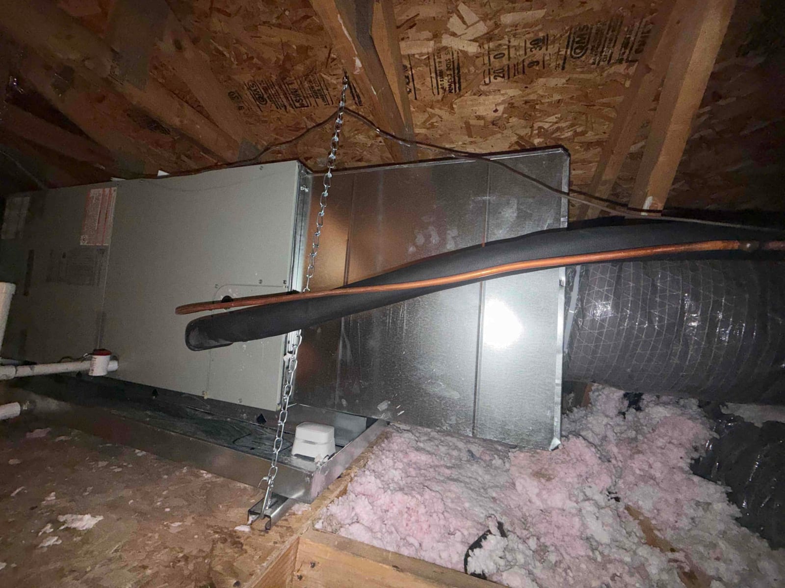 New attic air handler set in a drain pan with insulated refrigerant line and flex duct connected to the supply plenum.