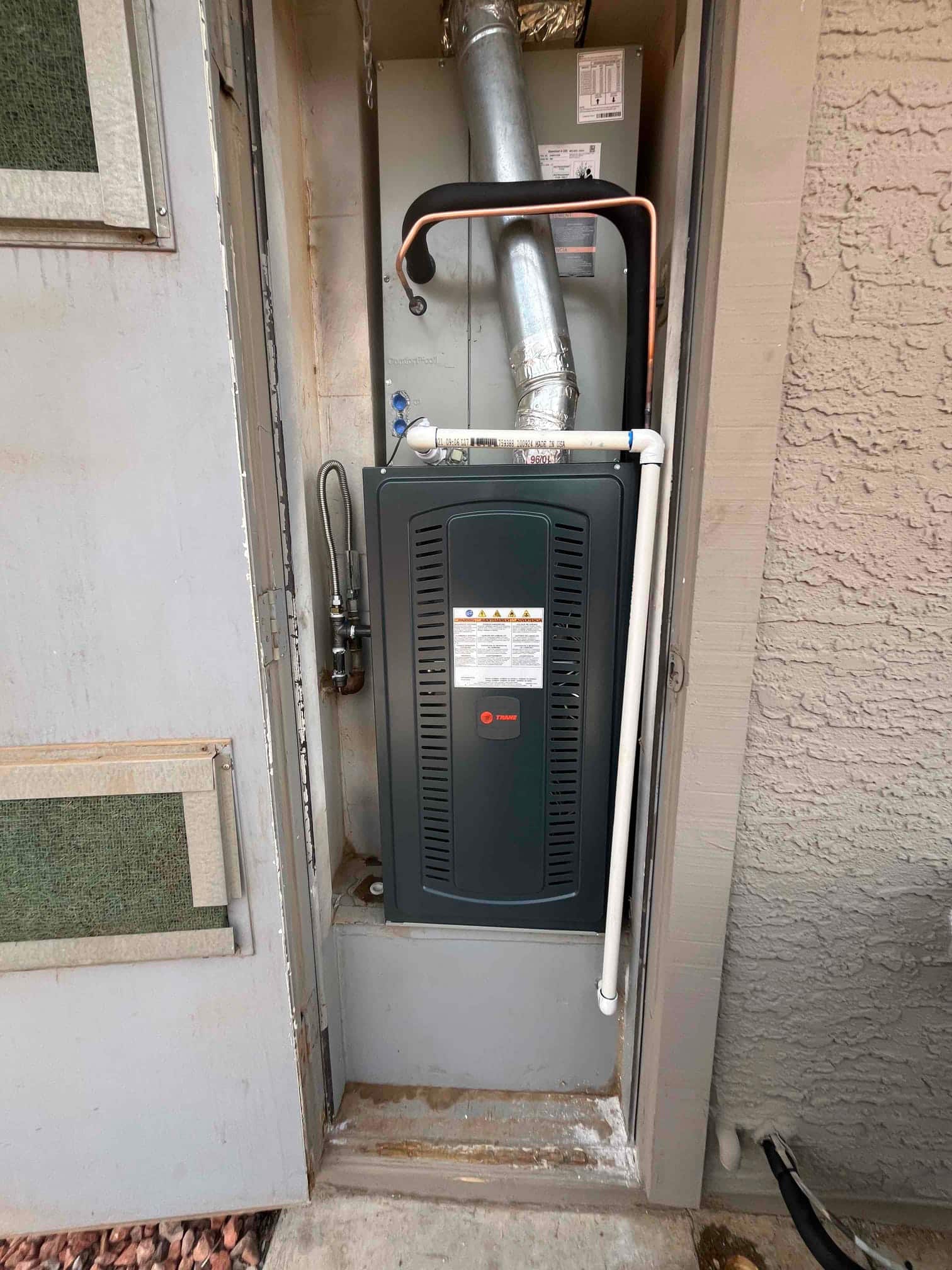 New furnace and coil cabinet installed in exterior closet with venting, condensate drain, gas line, and insulated refrigerant line.