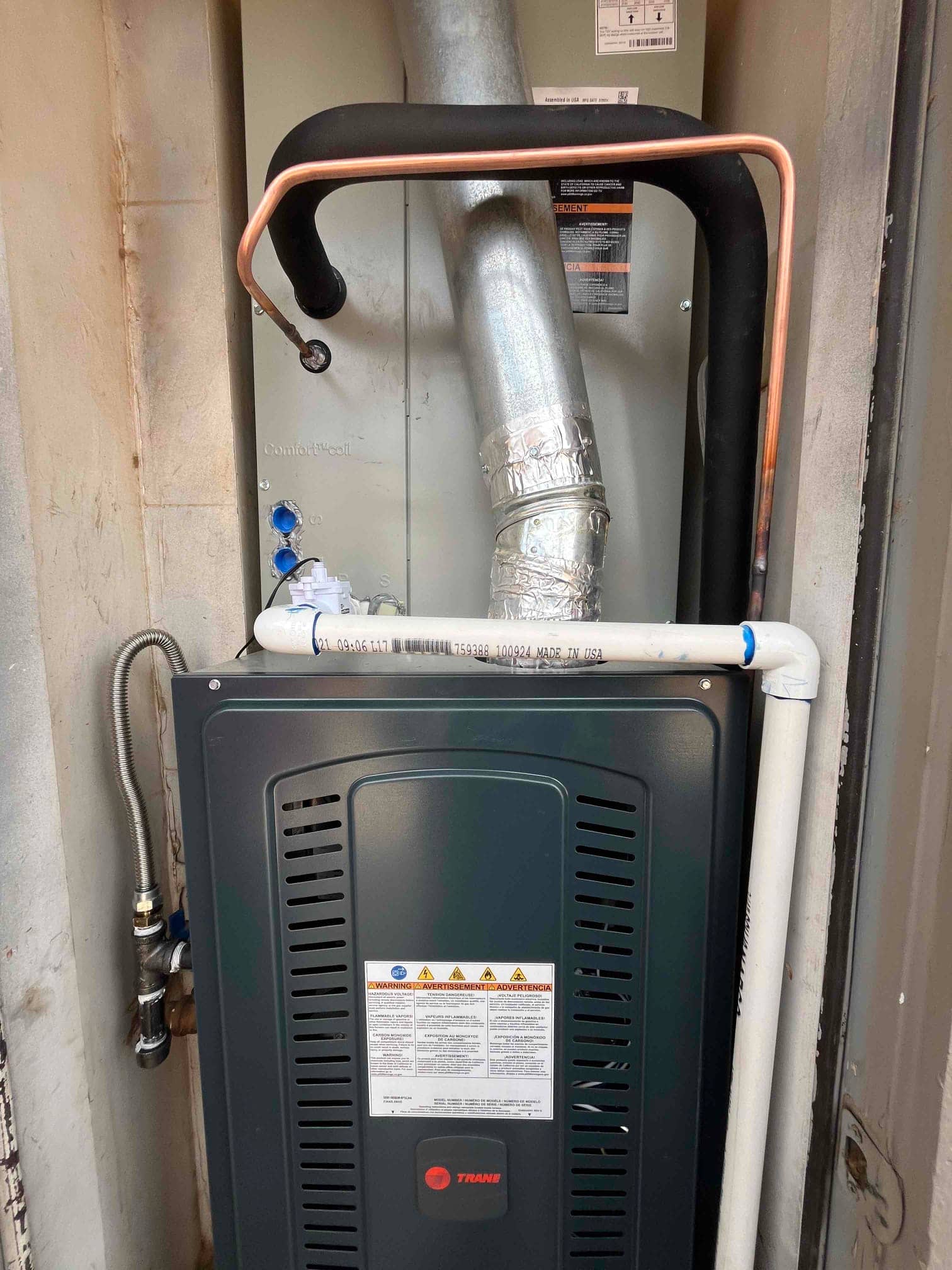 New gas furnace and evaporator cabinet installed with insulated refrigerant lines, condensate drain piping, and galvanized flue connection.