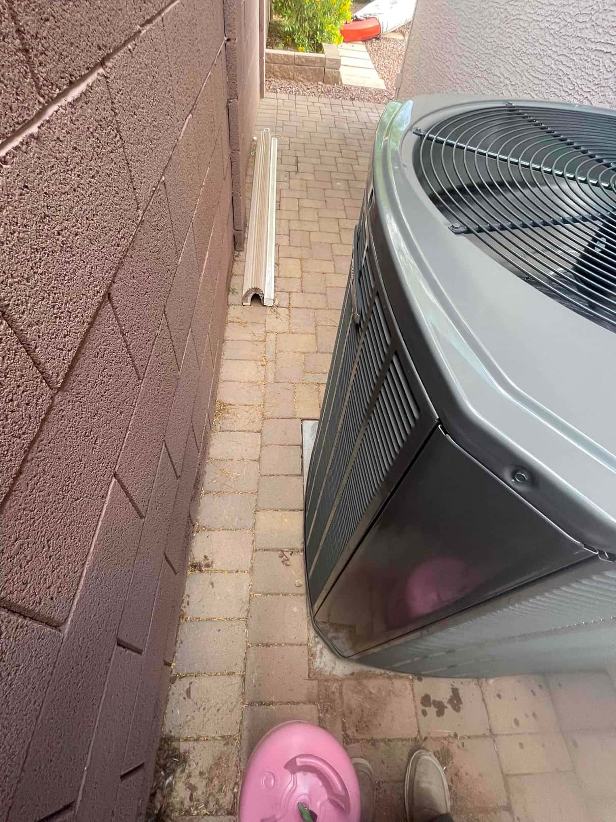 New outdoor condenser set on a level pad beside the house, with refrigerant cylinder and line-hide channel nearby.