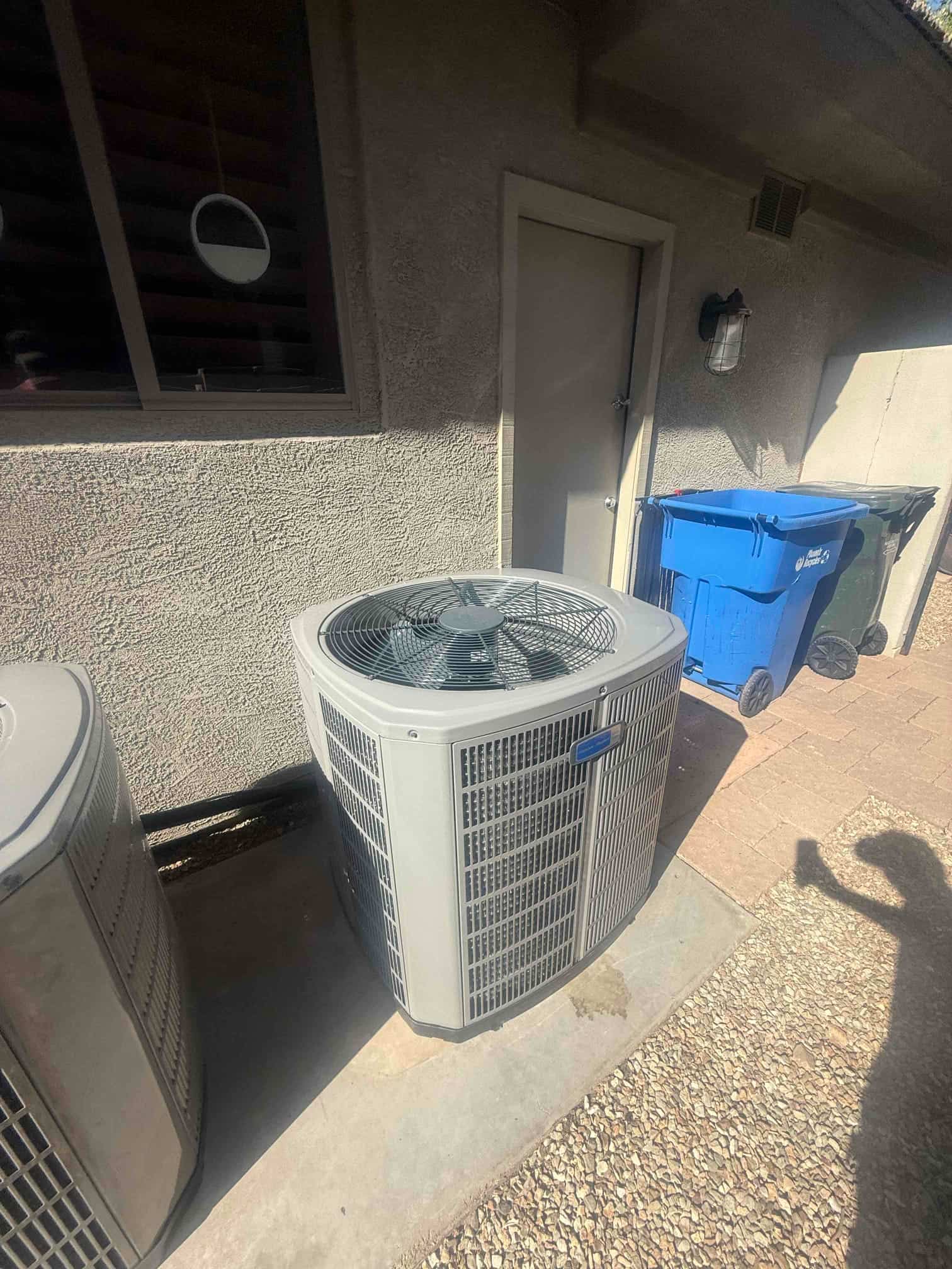 New outdoor condenser set on a level pad with insulated line set routed along the wall at the installation site.