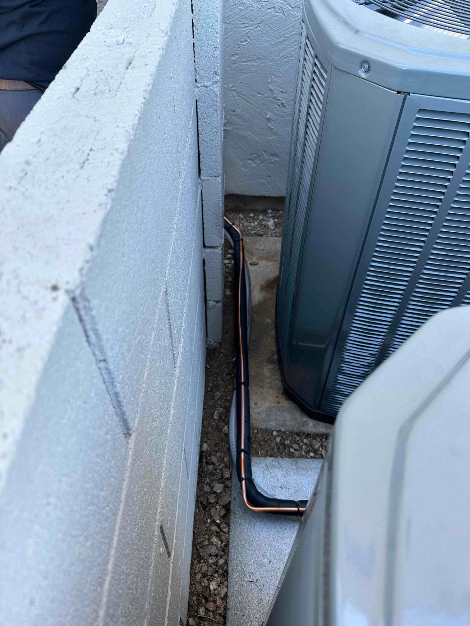 New outdoor condenser set on a pad with neatly routed insulated refrigerant line set along the wall clearance.