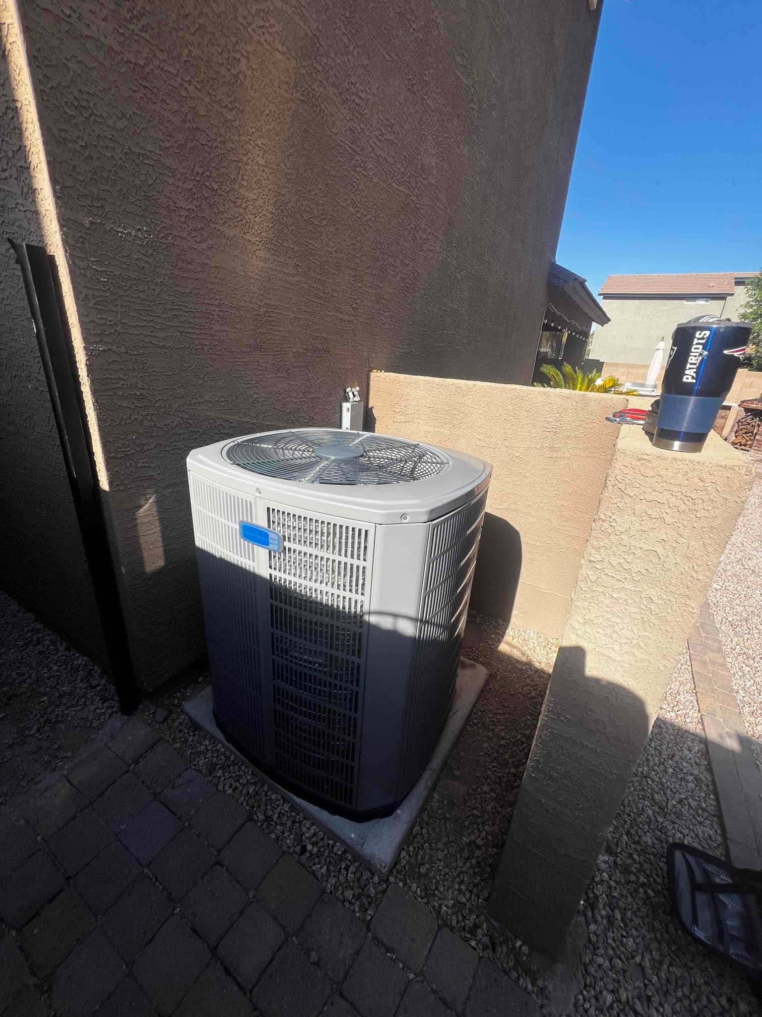 New outdoor heat pump condenser set on a level pad with clearances around the unit and nearby service disconnect.