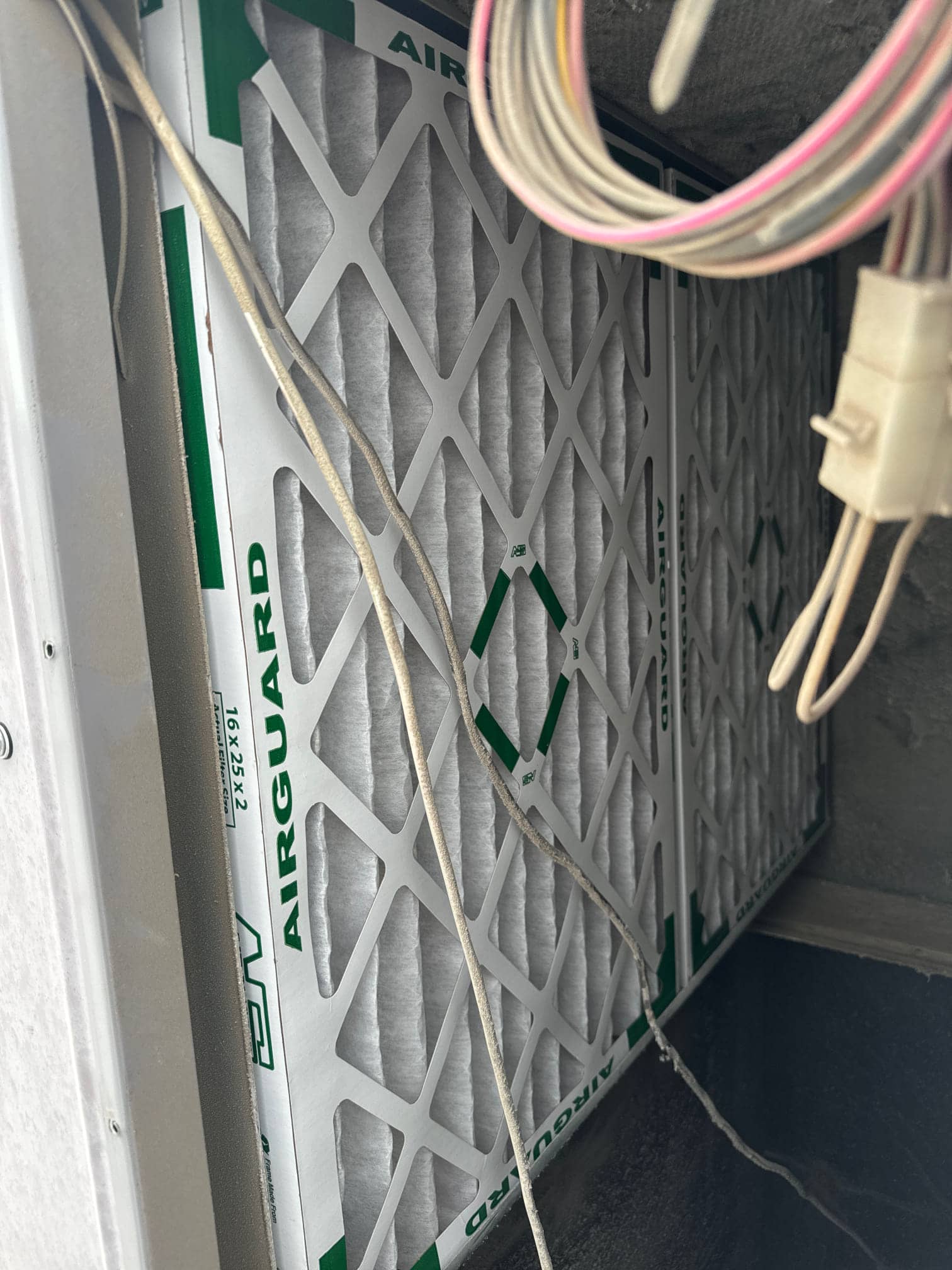 New pleated air filter installed in the air handler, showing clean media and surrounding wiring harness nearby.