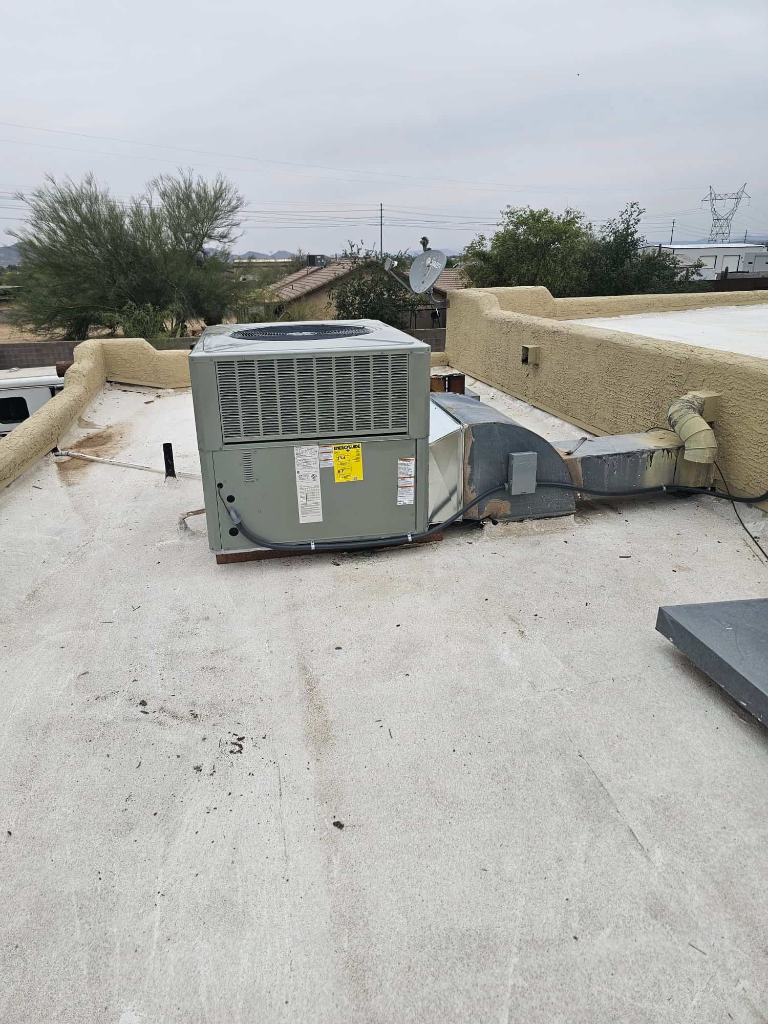 New rooftop packaged HVAC unit installed on a flat roof with connected duct transitions and sealed roof penetration.