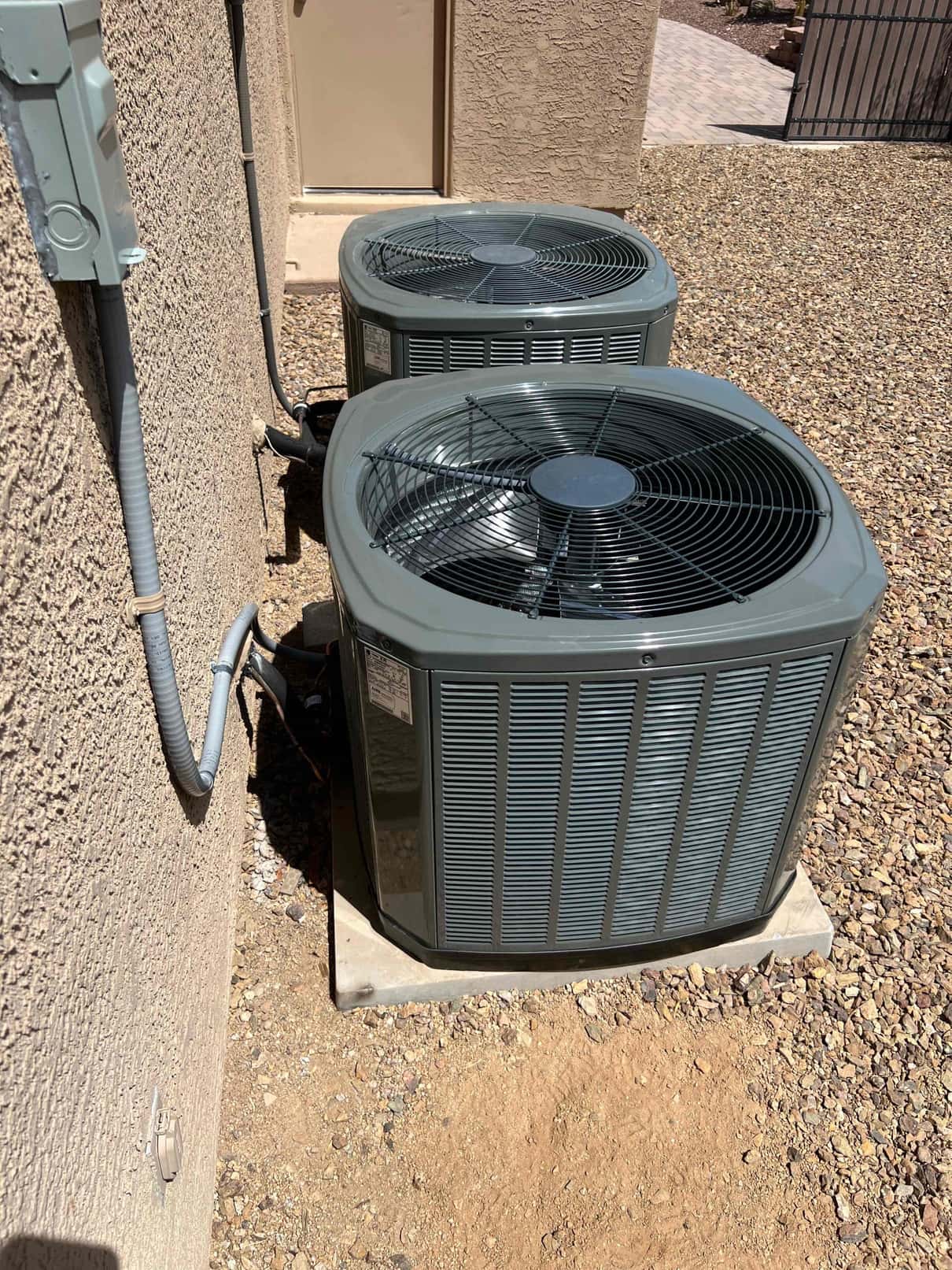 Two newly installed outdoor condensers set on level pads with insulated line sets and weatherproof electrical disconnects.