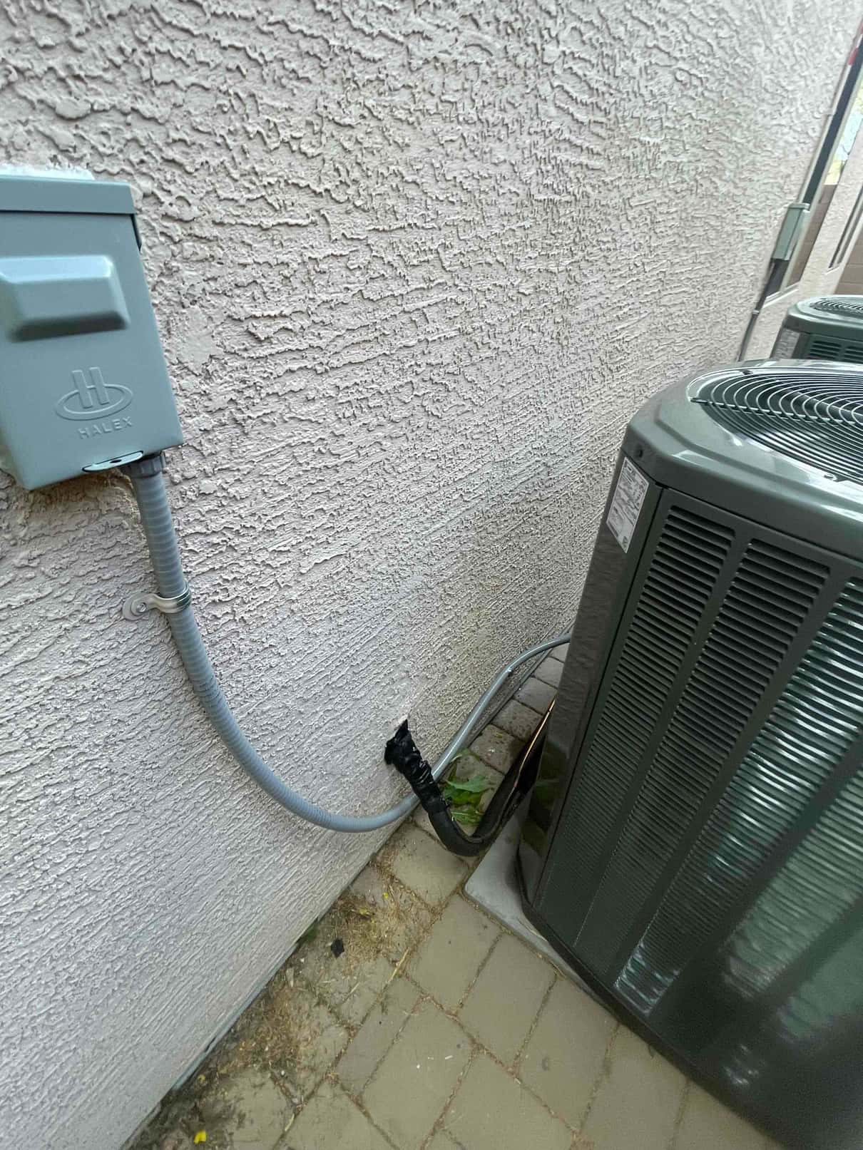Outdoor condenser installed on a level pad with electrical disconnect and insulated line set routed into the wall.