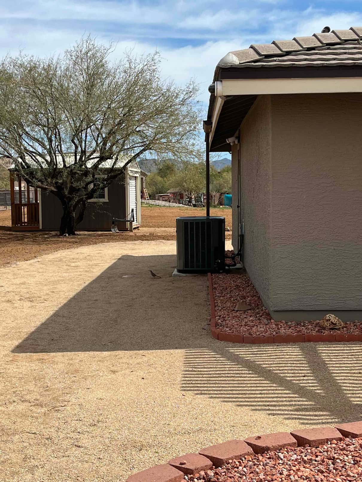 Outdoor condenser set on a level pad with insulated refrigerant lines and electrical whip connected alongside the home.