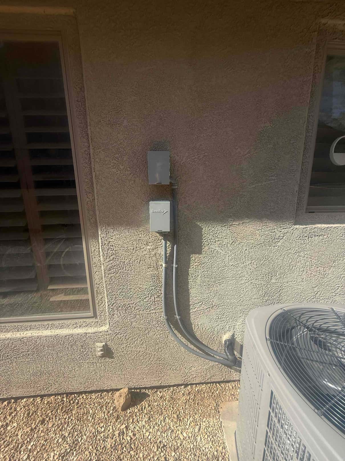 Outdoor condenser set on a pad with new electrical disconnect and sealed line set penetration into the exterior wall.