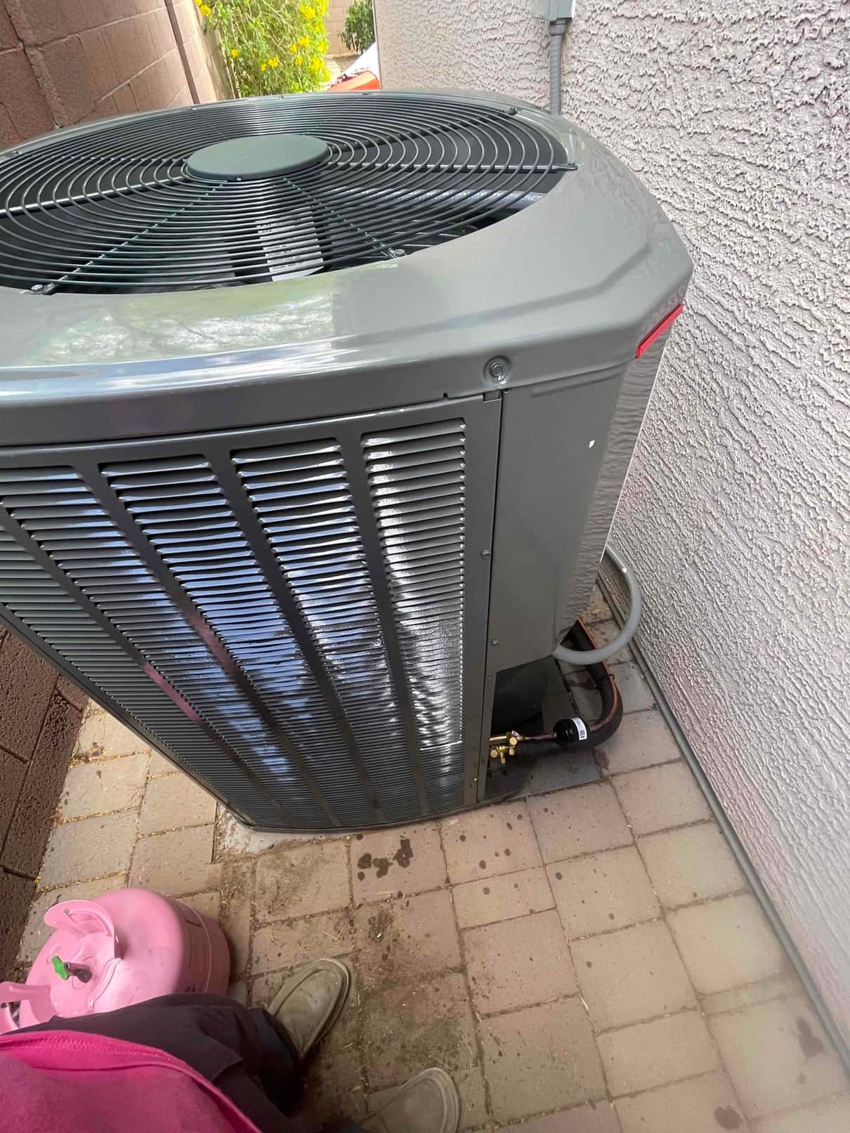 Outdoor condenser set on a paver pad with insulated refrigerant lines connected and a filter drier installed at the service valves.