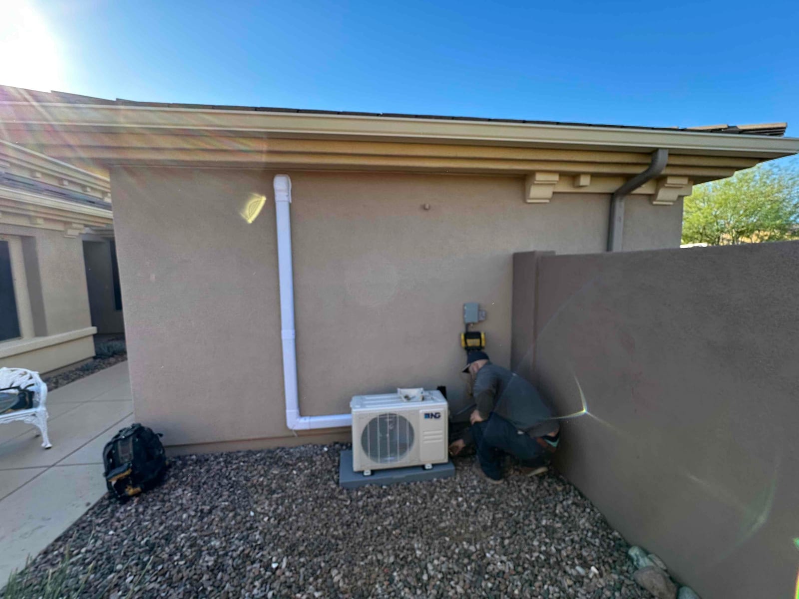 Outdoor mini-split condenser set on a level pad with line-set cover and electrical disconnect installed beside it.