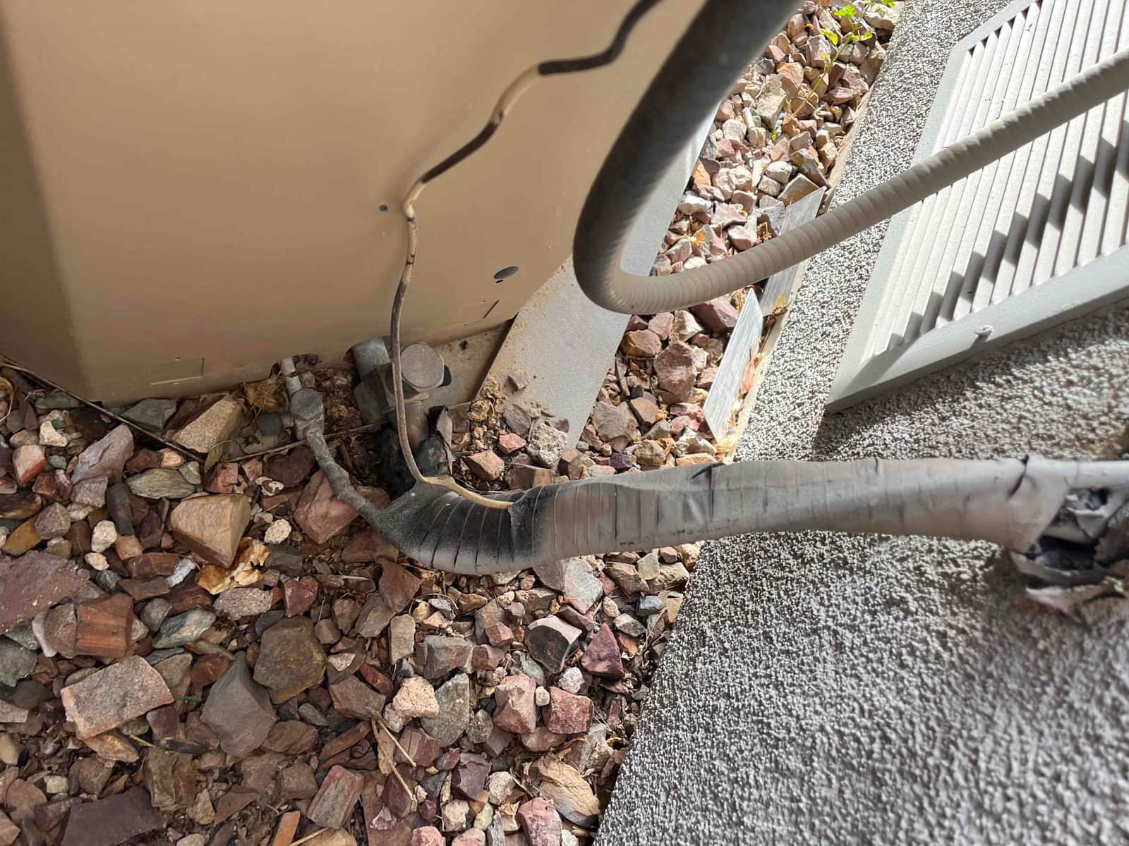 Refrigerant line set at outdoor condenser with cracked insulation and exposed tape near service valves.