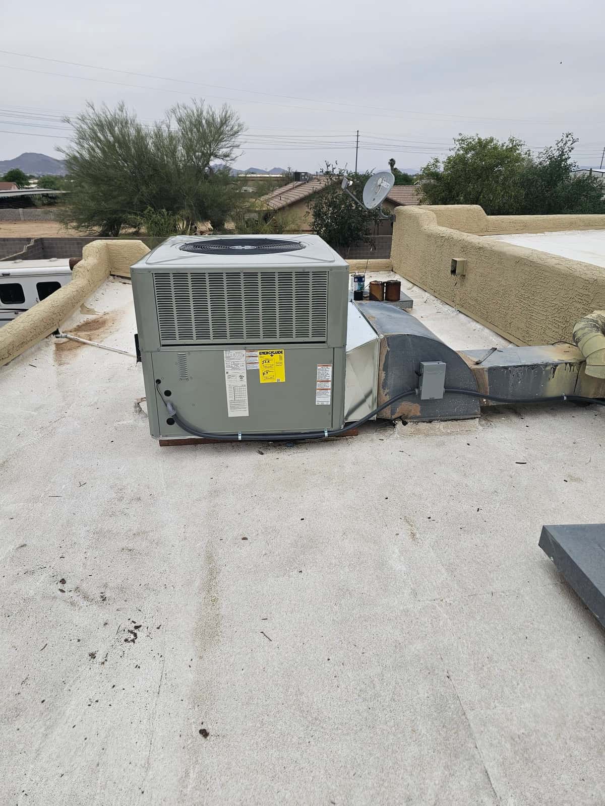 Rooftop packaged HVAC unit newly set on the roof with connected ductwork, electrical whip, and sealed roof penetration.
