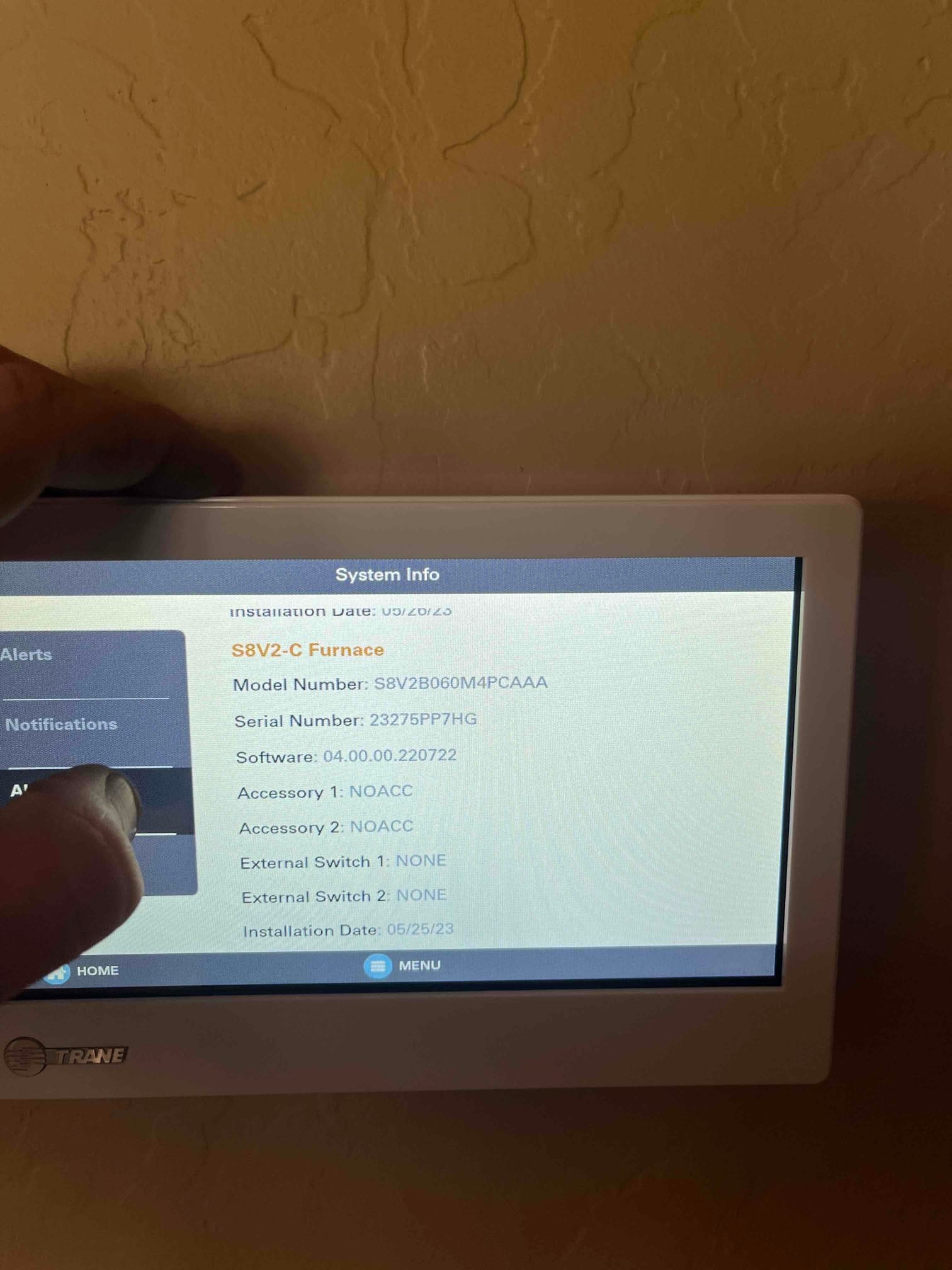 Thermostat touchscreen displays system information for the installed furnace, with a technician’s hand interacting with the menu.