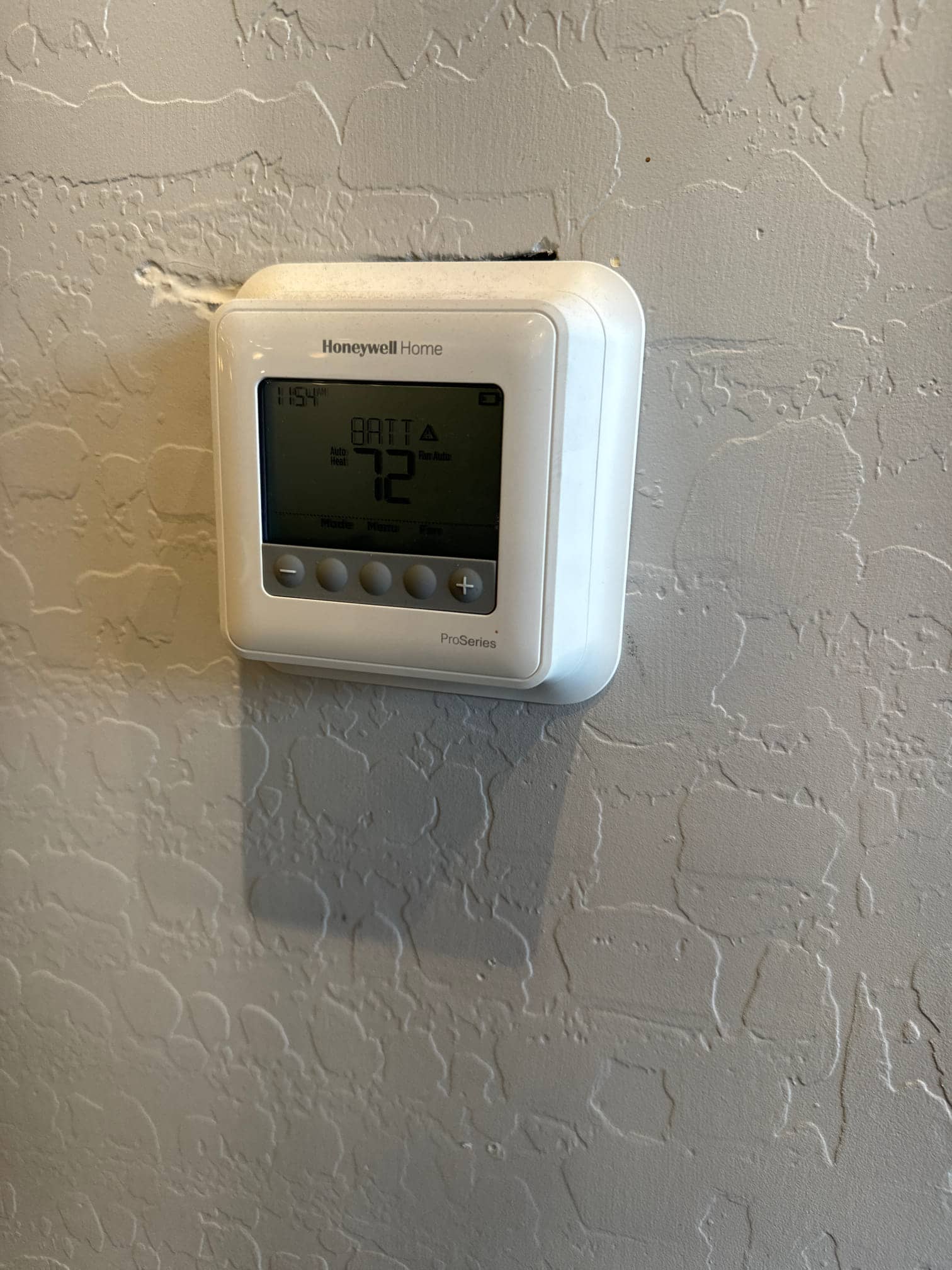 Wall-mounted digital thermostat display shows system in heat mode with a setpoint of 72 degrees.