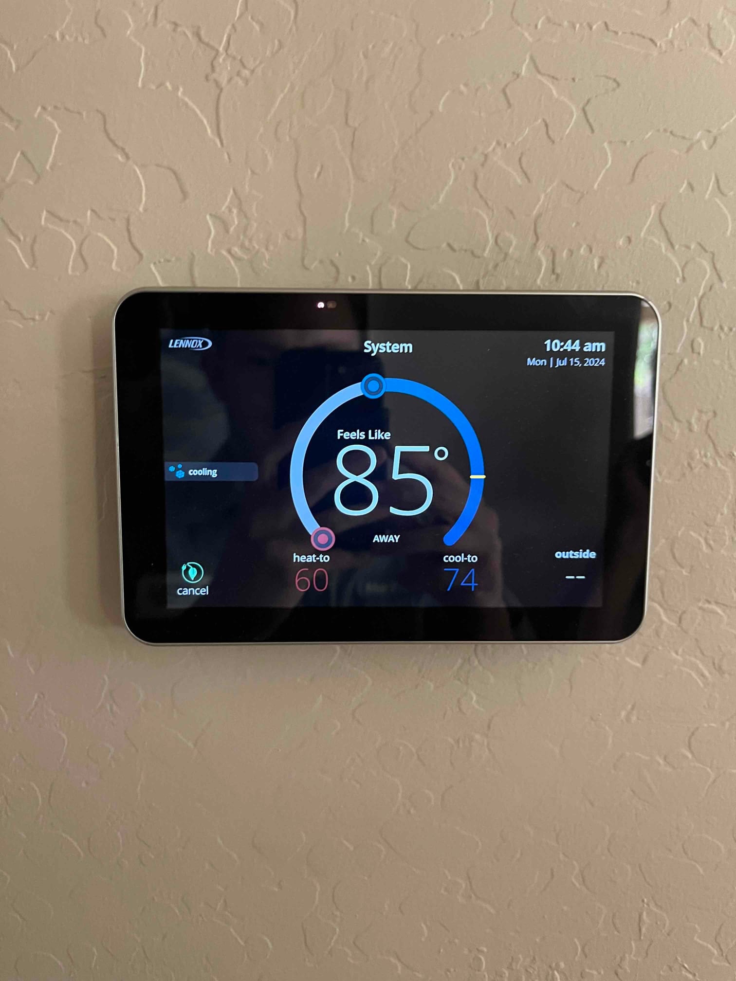 Wall-mounted thermostat display shows cooling mode active with indoor temperature reading 85°, heat-to 60°, and cool-to 74°.