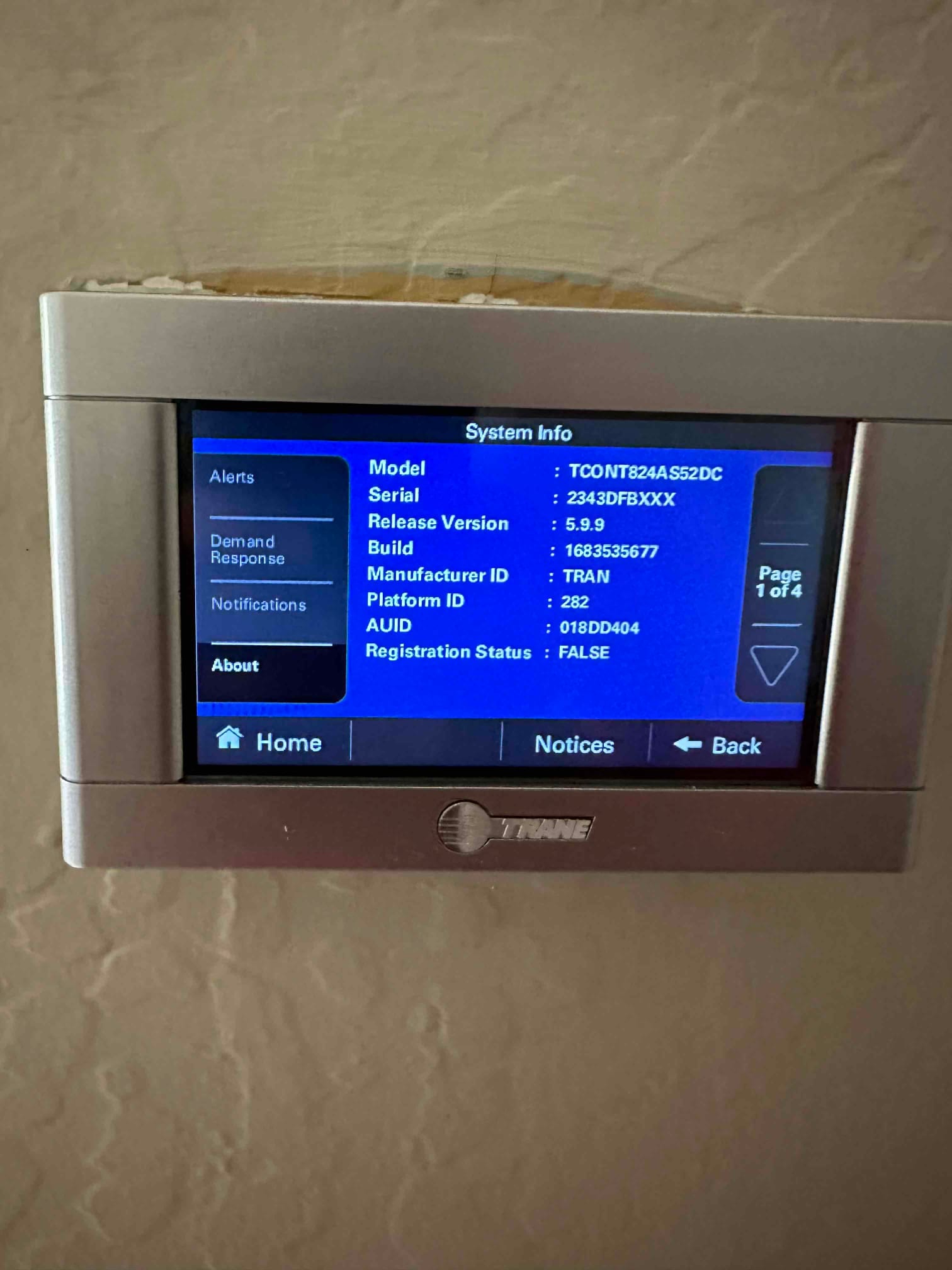 Wall-mounted thermostat displays system information screen after installation, showing model details and menu options on the interface.