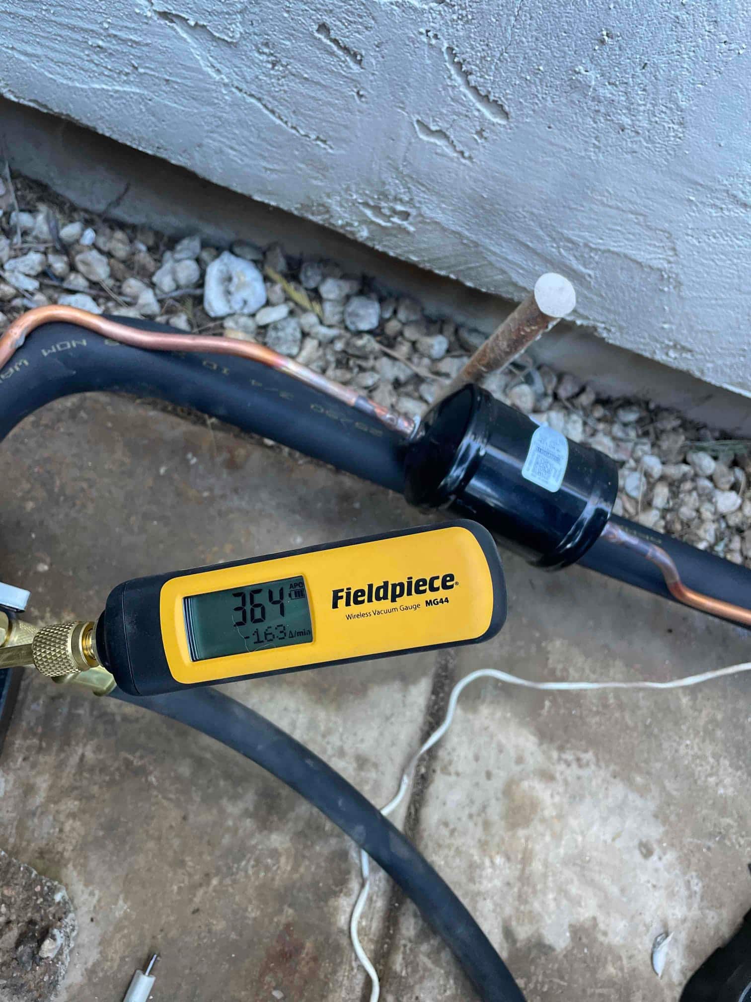Wireless vacuum gauge connected to the line set shows 364 microns during system evacuation before refrigerant charging.