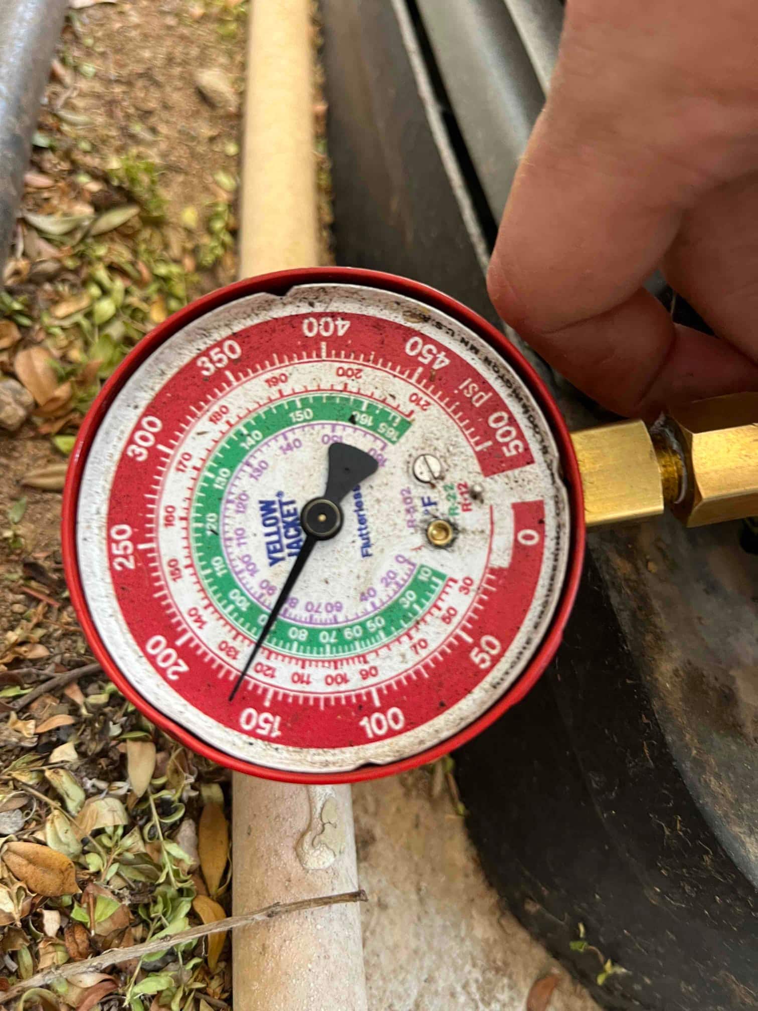 Analog manifold gauge connected at the service port shows low-side pressure reading of 95 psi during air conditioning operation.