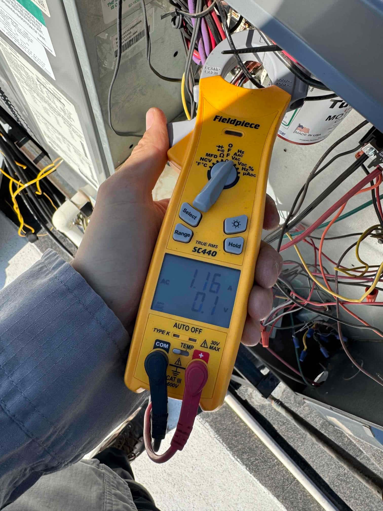 Clamp meter displays 1.6 A on a single conductor at the outdoor condenser’s open control panel.