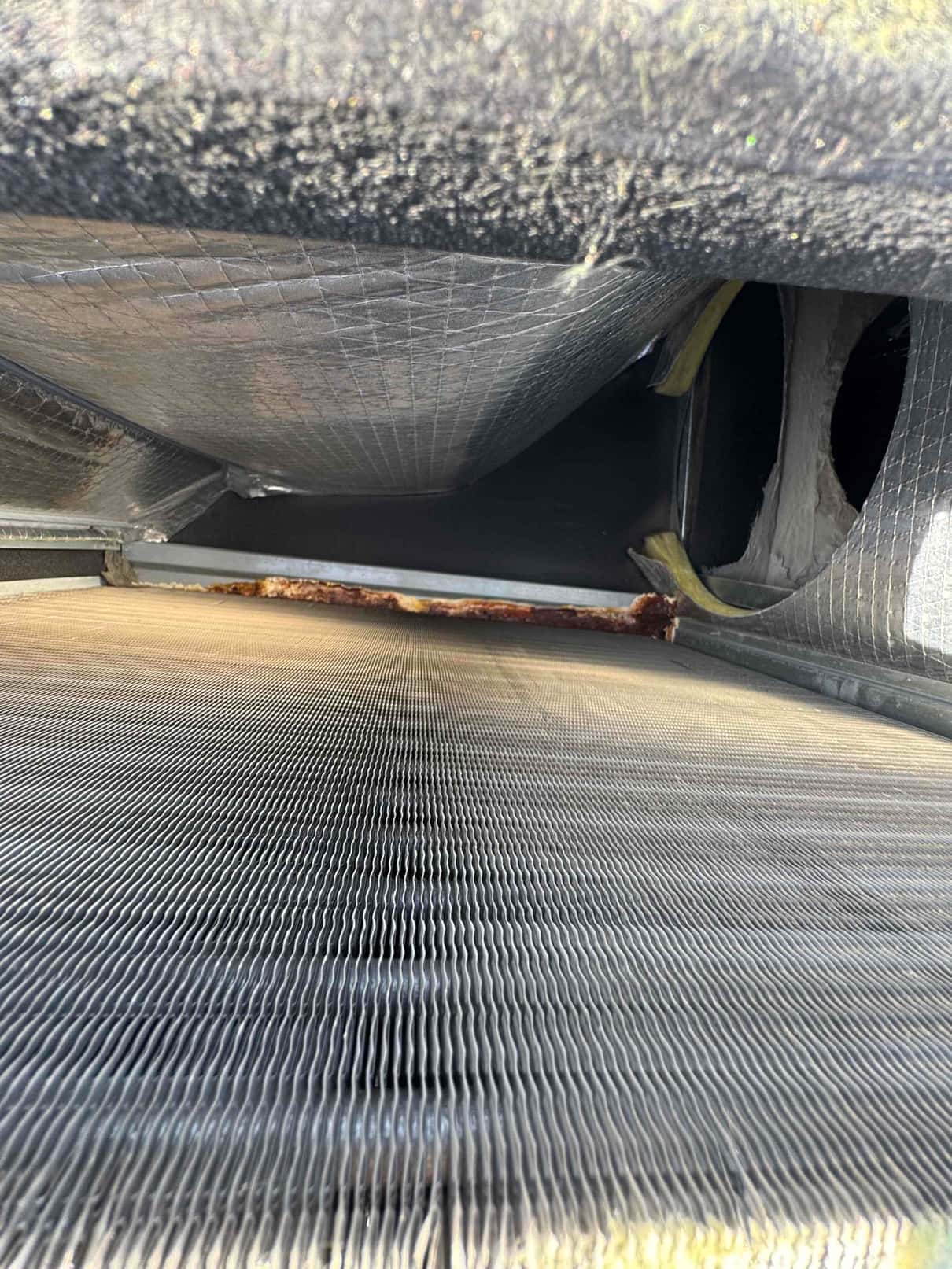 Close-up view inside an outdoor condenser unit showing the aluminum coil fins and interior housing surfaces.