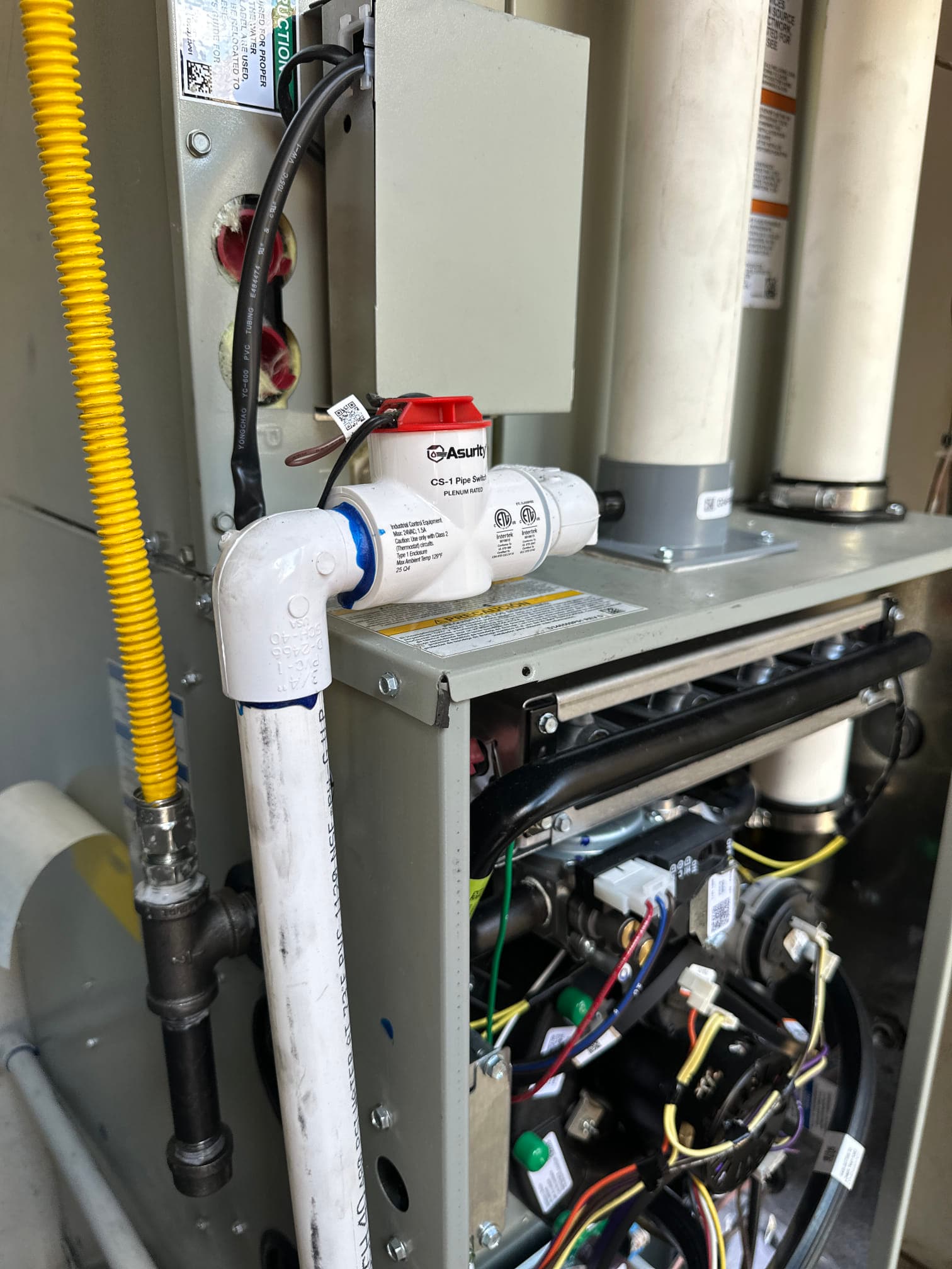 Condensate drain with inline safety switch plumbed to a newly installed gas furnace, showing clean wiring and vent piping.