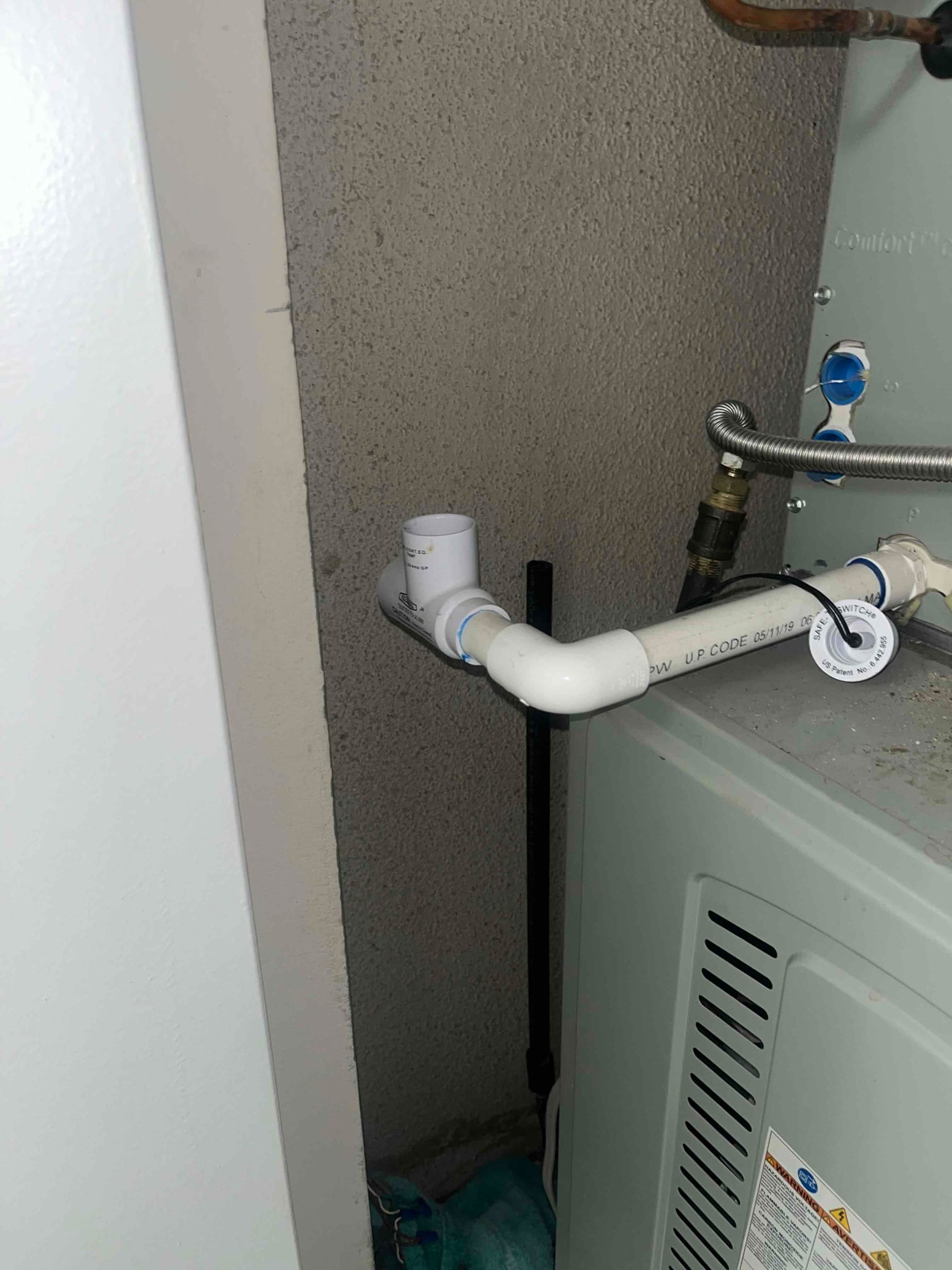 Condensate drain line repair completed with new PVC elbow, union, and cleanout on the air handler outlet.