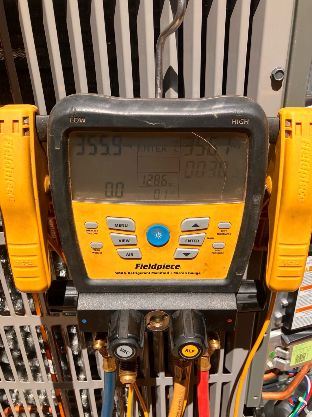 Digital manifold attached at the condenser shows both high and low sides holding the same pressure during a nitrogen pressure test.