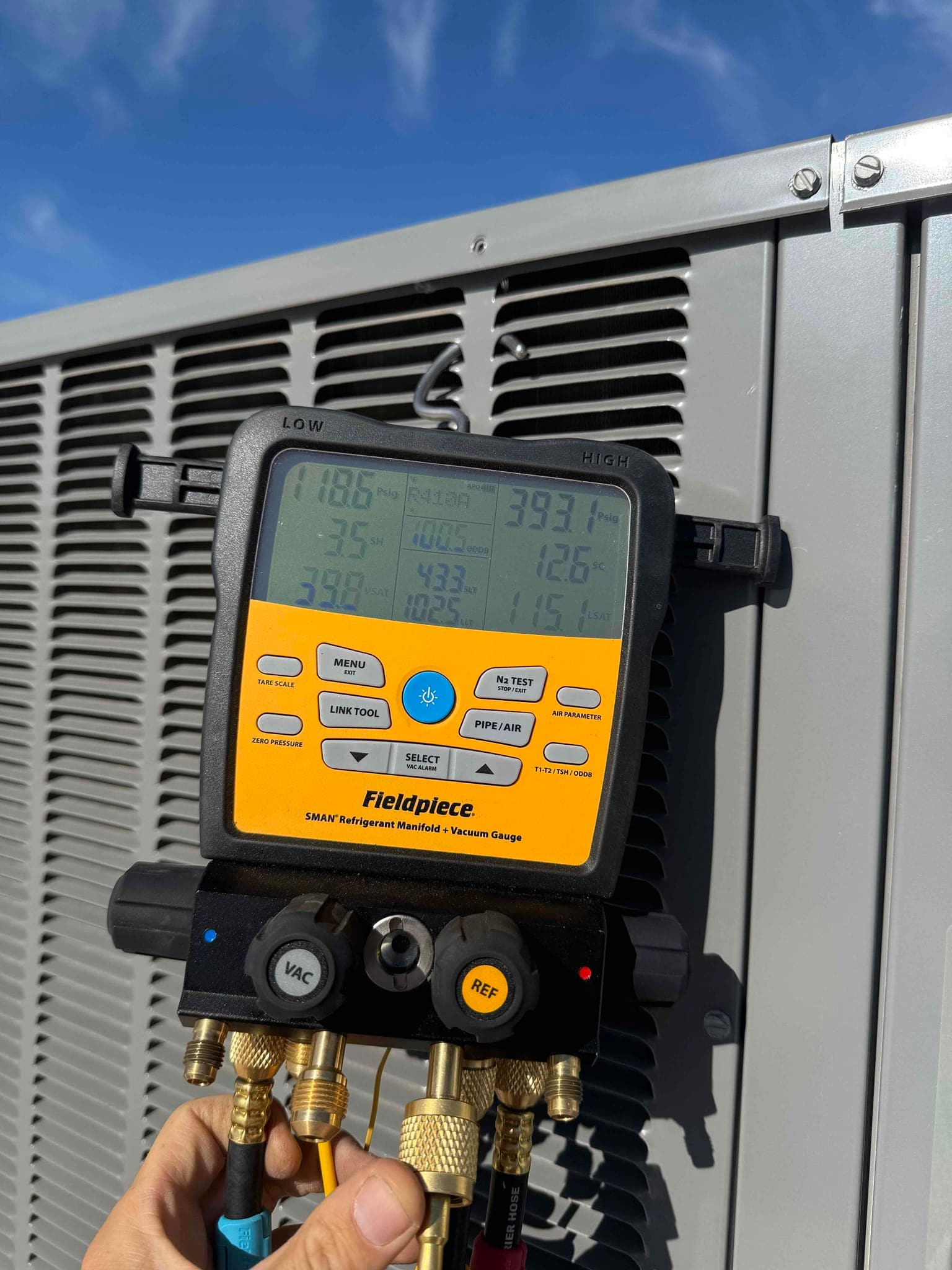 Digital manifold gauge connected to an outdoor condenser shows 393.1 psi on the high-side pressure port.