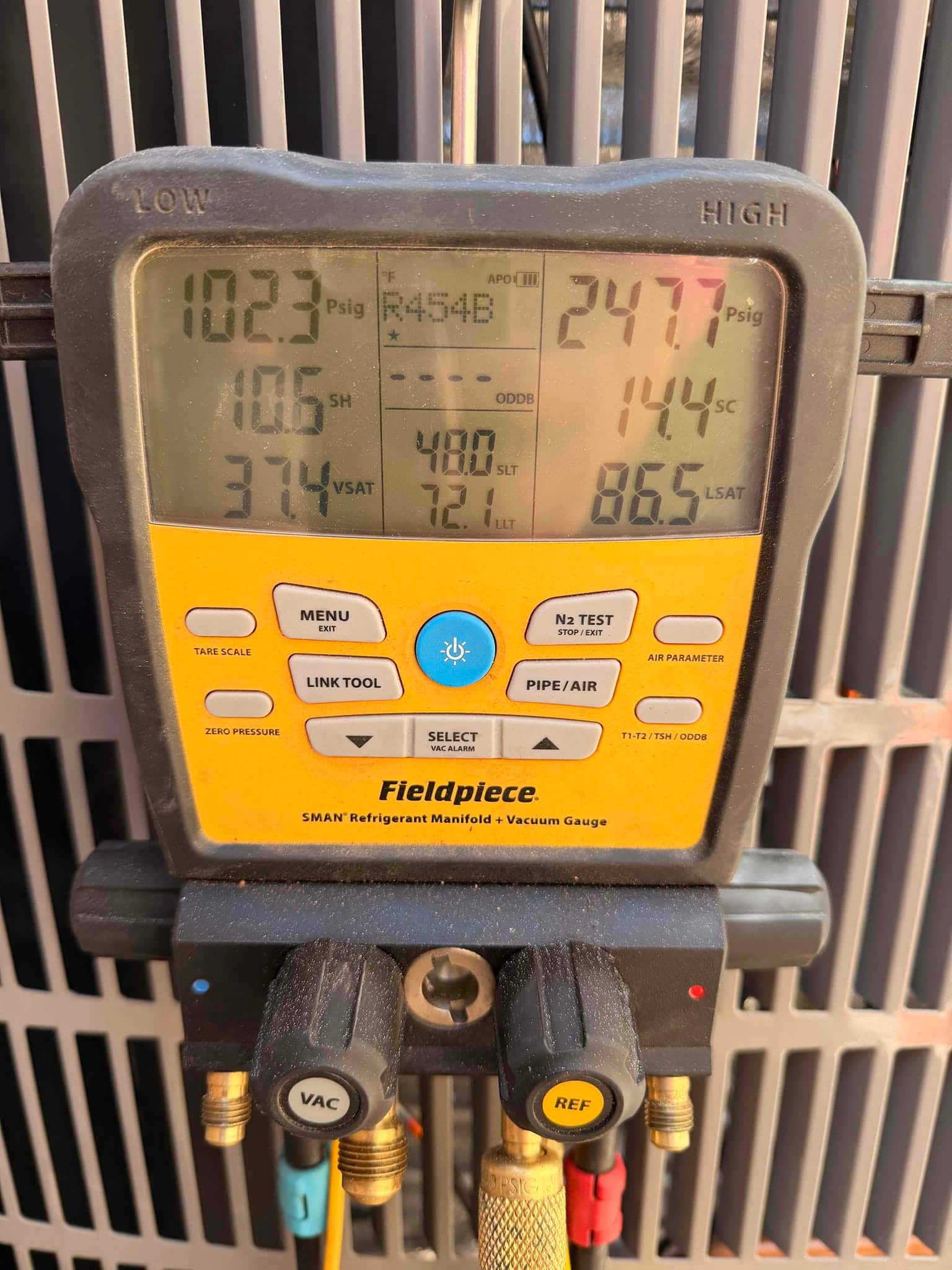 Digital manifold shows system operating pressures with R-454B selected, documenting low and high side readings during commissioning.