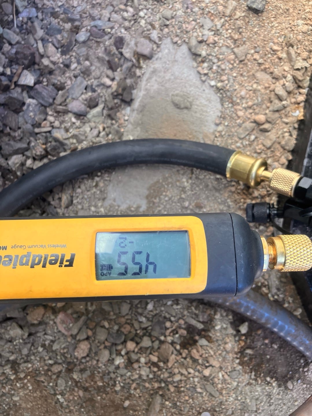 Digital micron gauge connected to the system shows a deep vacuum during the evacuation phase before refrigerant charging.