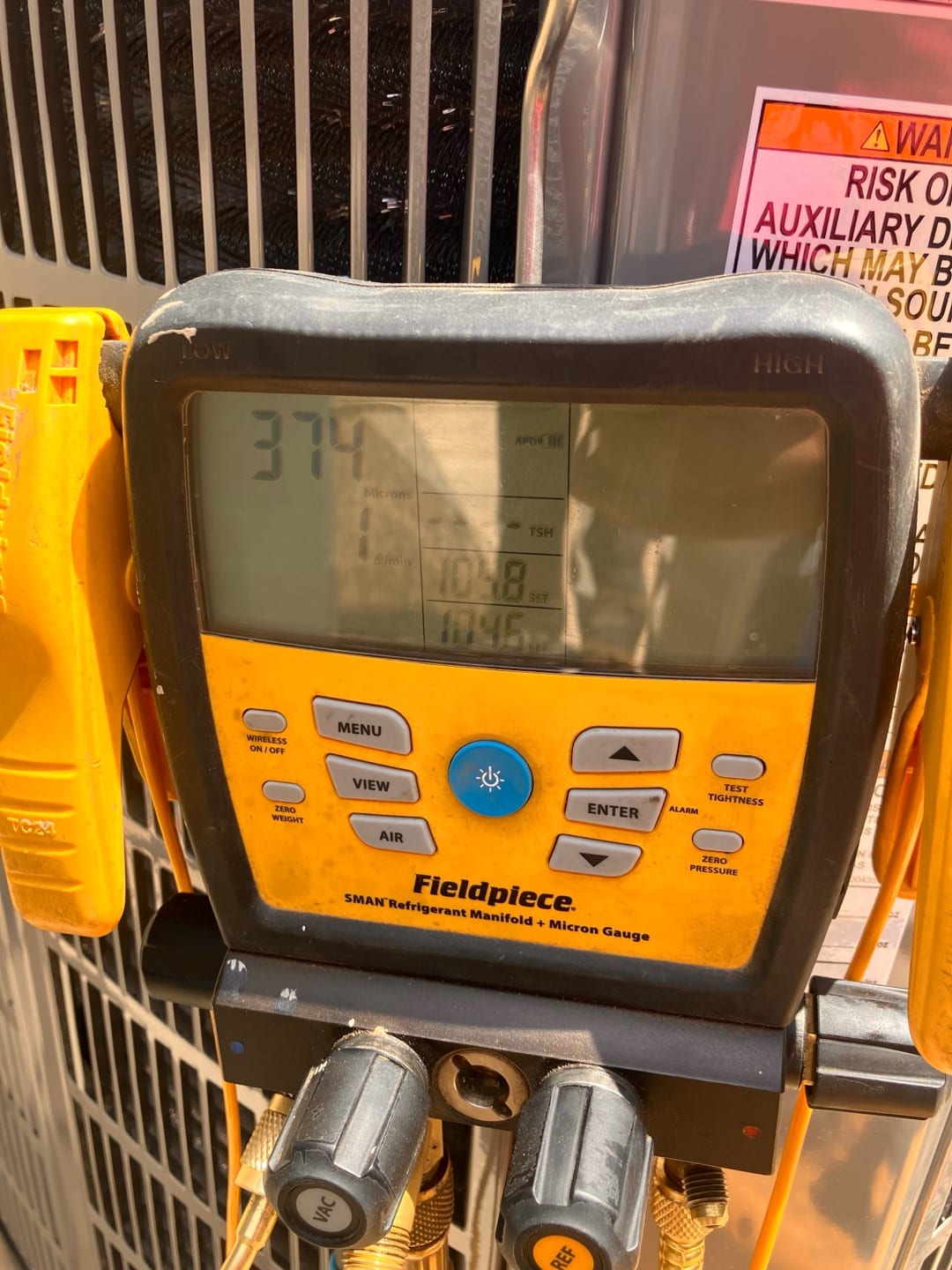Digital micron gauge on the manifold shows 374 microns during system evacuation prior to refrigerant charging.