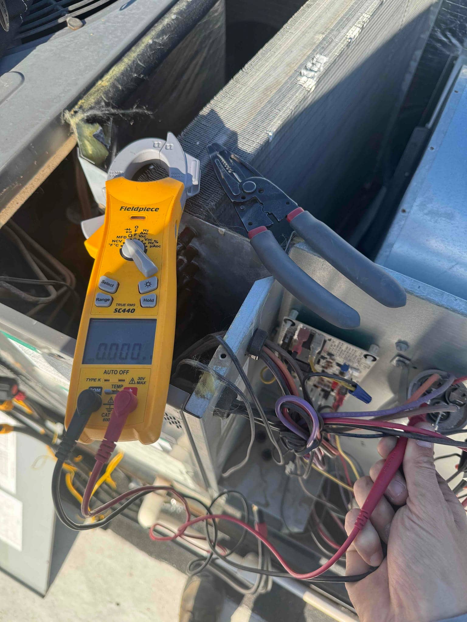 Digital multimeter measures 0.00 V at the contactor terminals on the outdoor condenser control circuit.