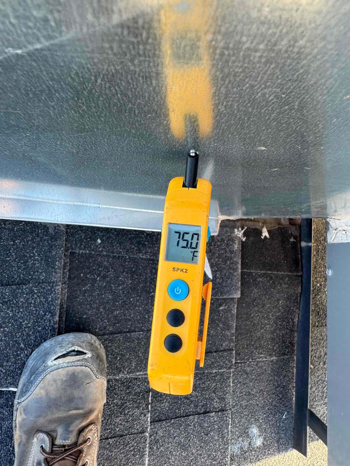 Digital thermometer probe measures a surface temperature of 75.0 °F on the HVAC equipment housing.