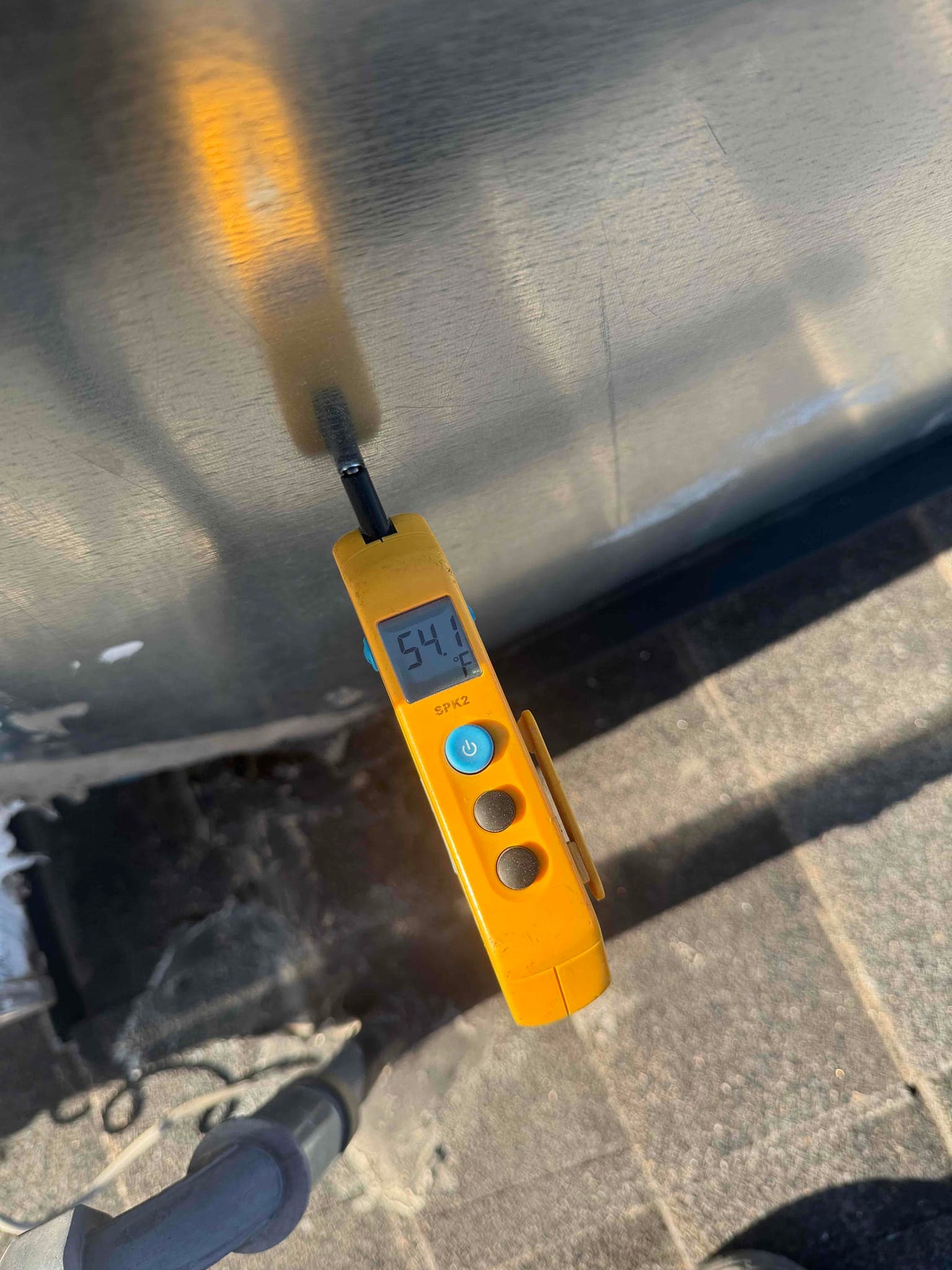 Digital thermometer shows 54 °F surface temperature on the exterior panel of the outdoor condenser unit.