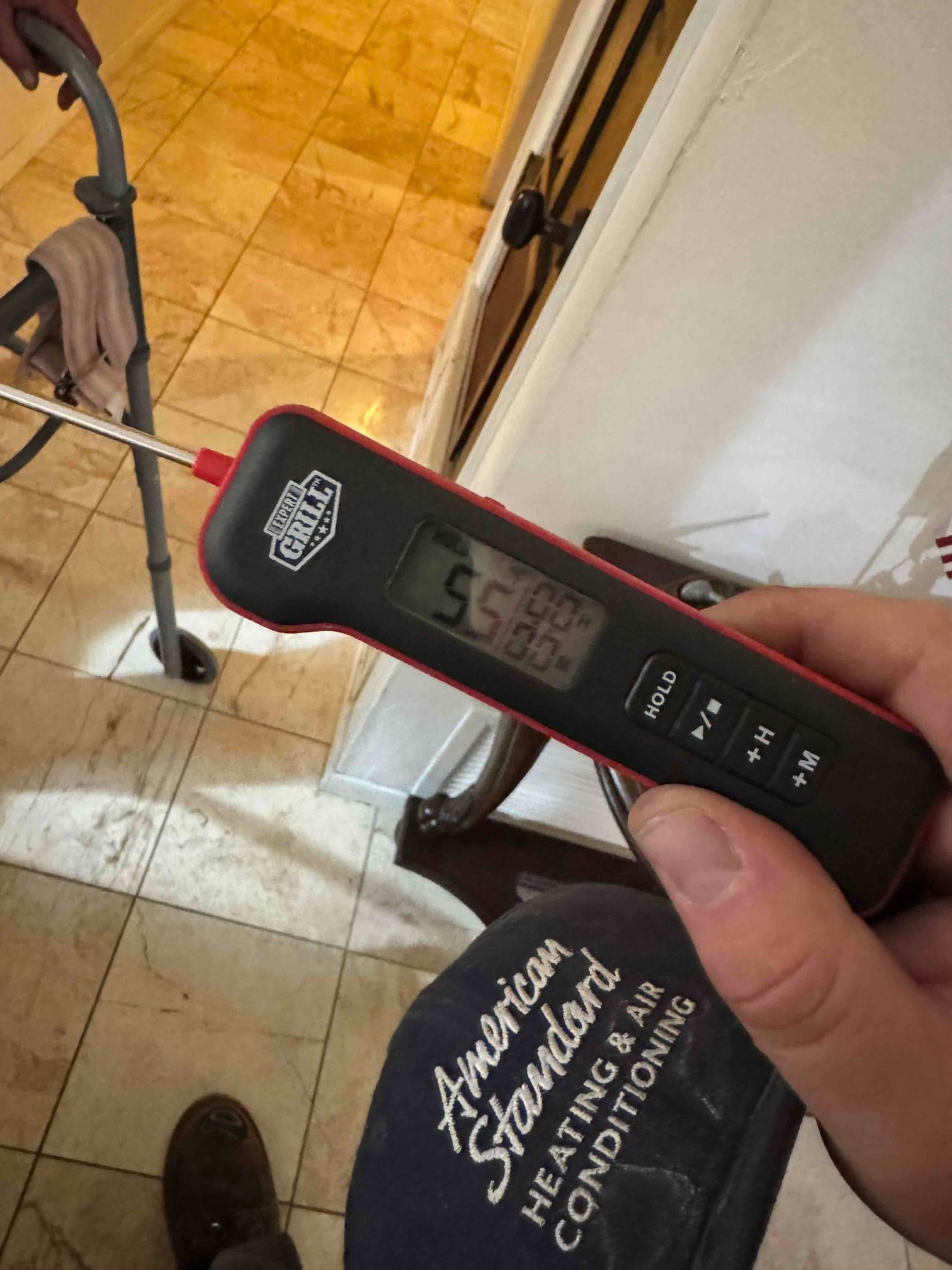 Digital thermometer shows 55.2 °F air temperature at the probe tip during air conditioning repair.