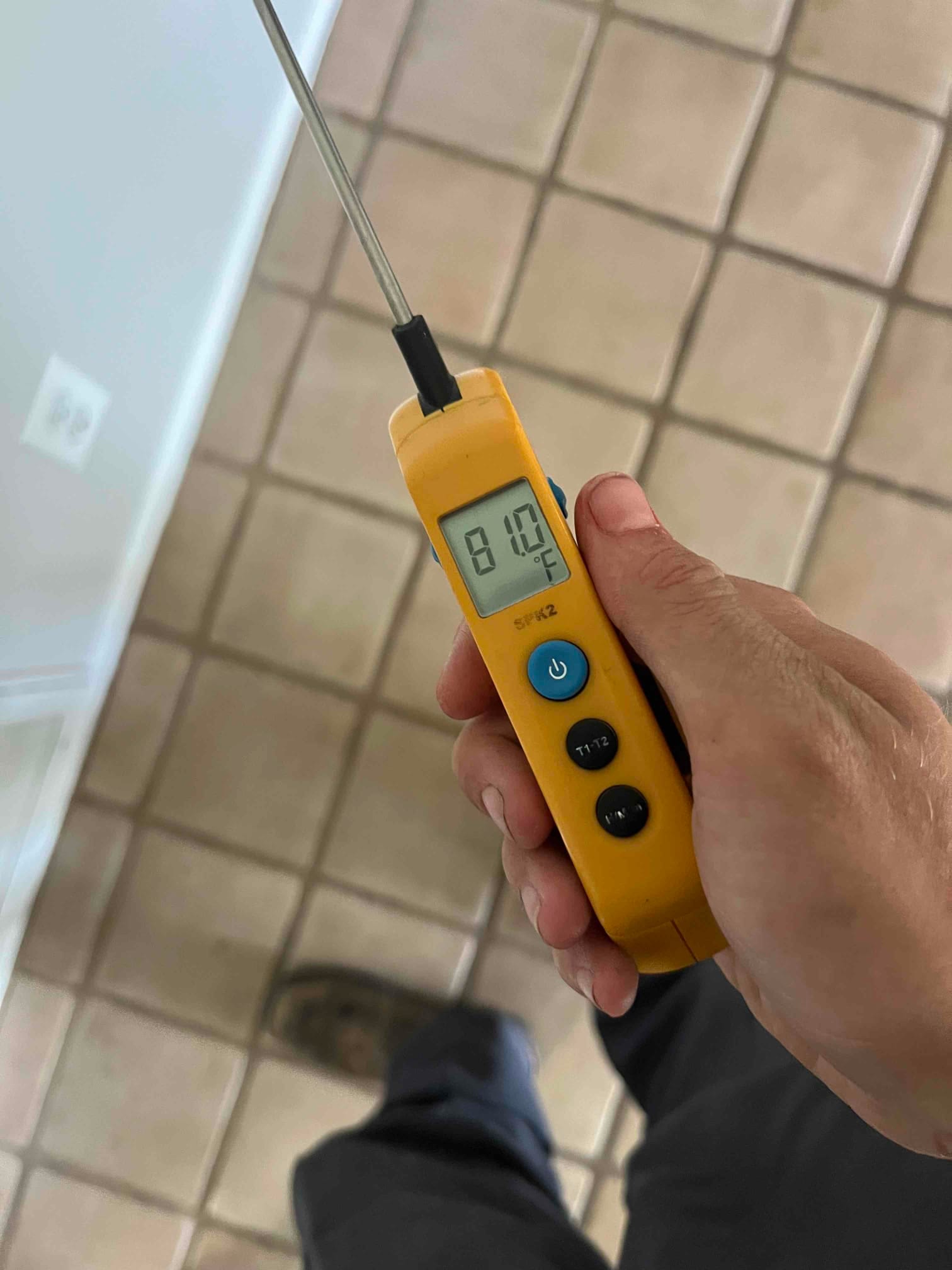 Digital thermometer shows 81.0 °F while measuring air temperature during the air conditioning repair visit.
