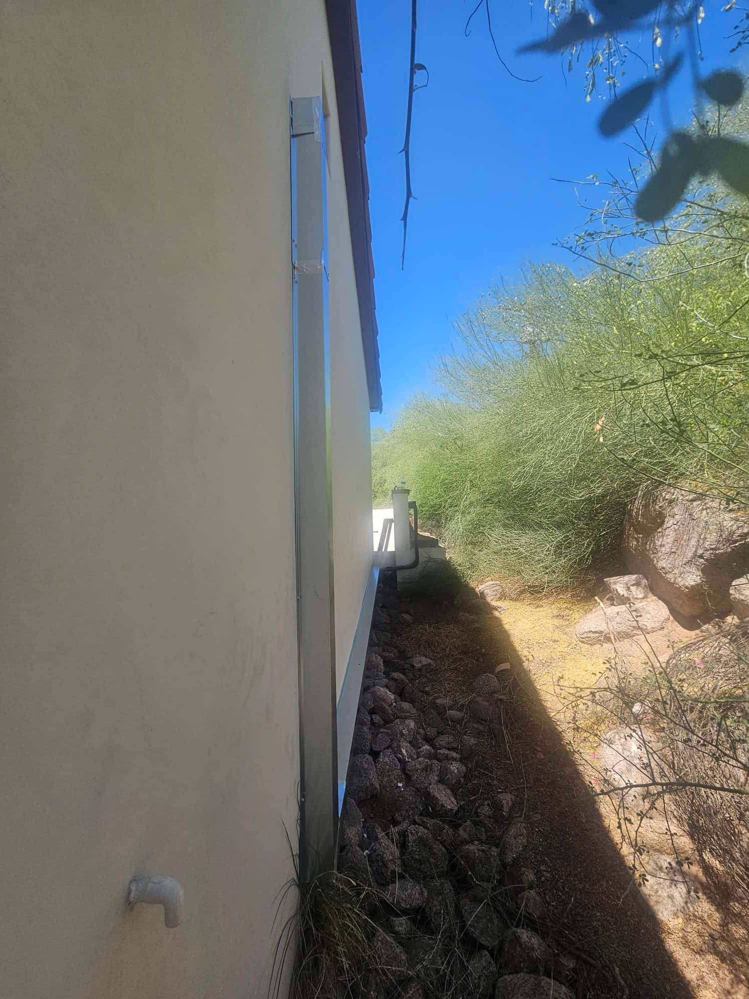 Exterior wall shows newly installed line set cover running vertically with sealed wall penetration beside the outdoor unit location.