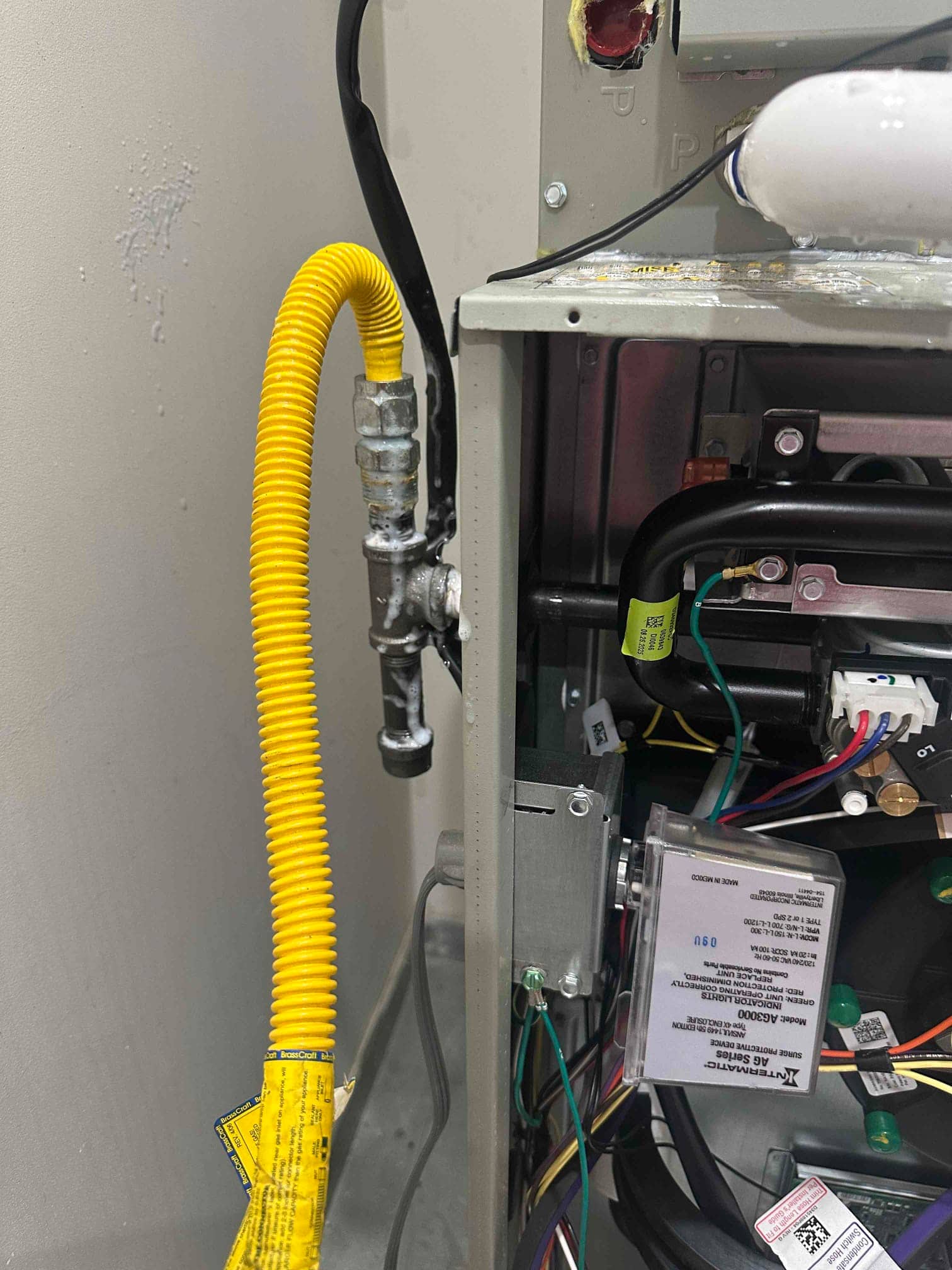 Gas flex connector, shutoff valve, and furnace wiring at the new indoor unit, with soap solution showing leak check on fittings.