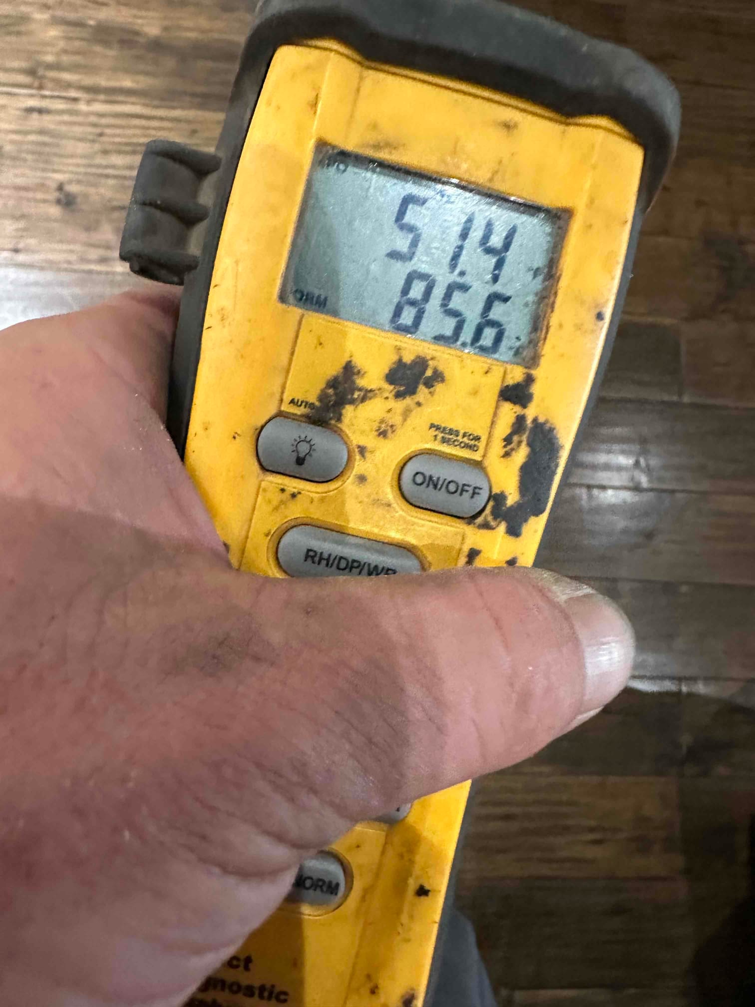 Handheld digital thermometer shows 51.4 degrees on the top line and 85.6 degrees on the lower line during airflow checks.