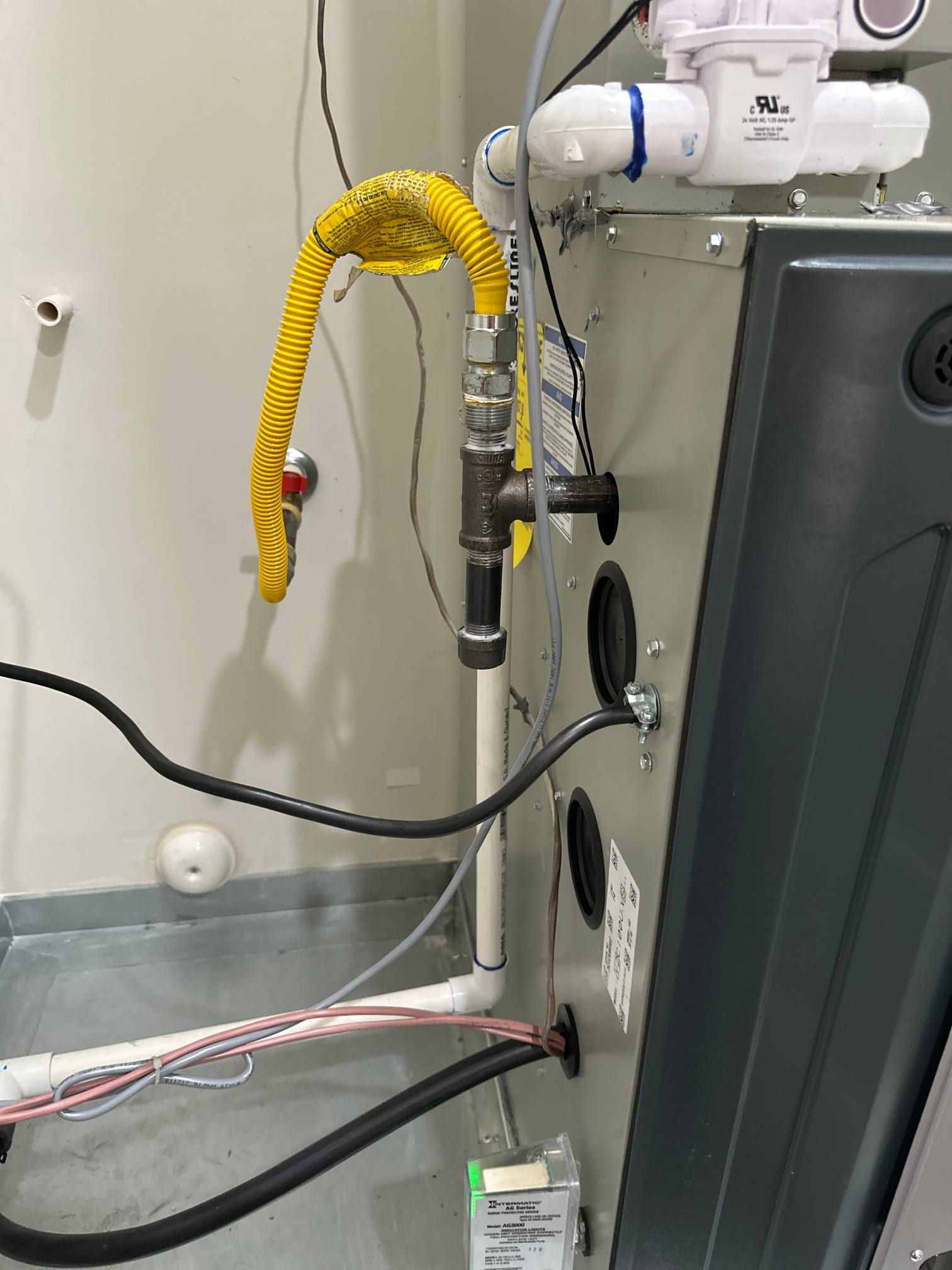 Indoor furnace installation with gas flex connector, condensate drain piping, wiring penetrations, and LED indicator on the control module.