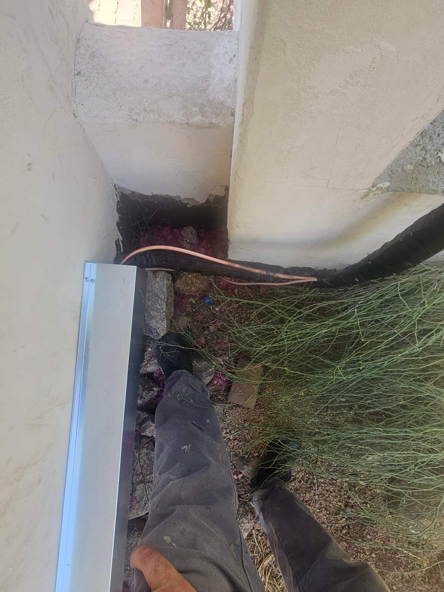 Insulated refrigerant line set routed along exterior wall and through sealed penetration during new air conditioning installation.